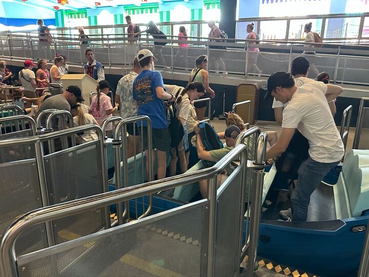 Guests board new boats for "it’s a small world" at the indoor Magic Kingdom ride, while others wait behind railings.