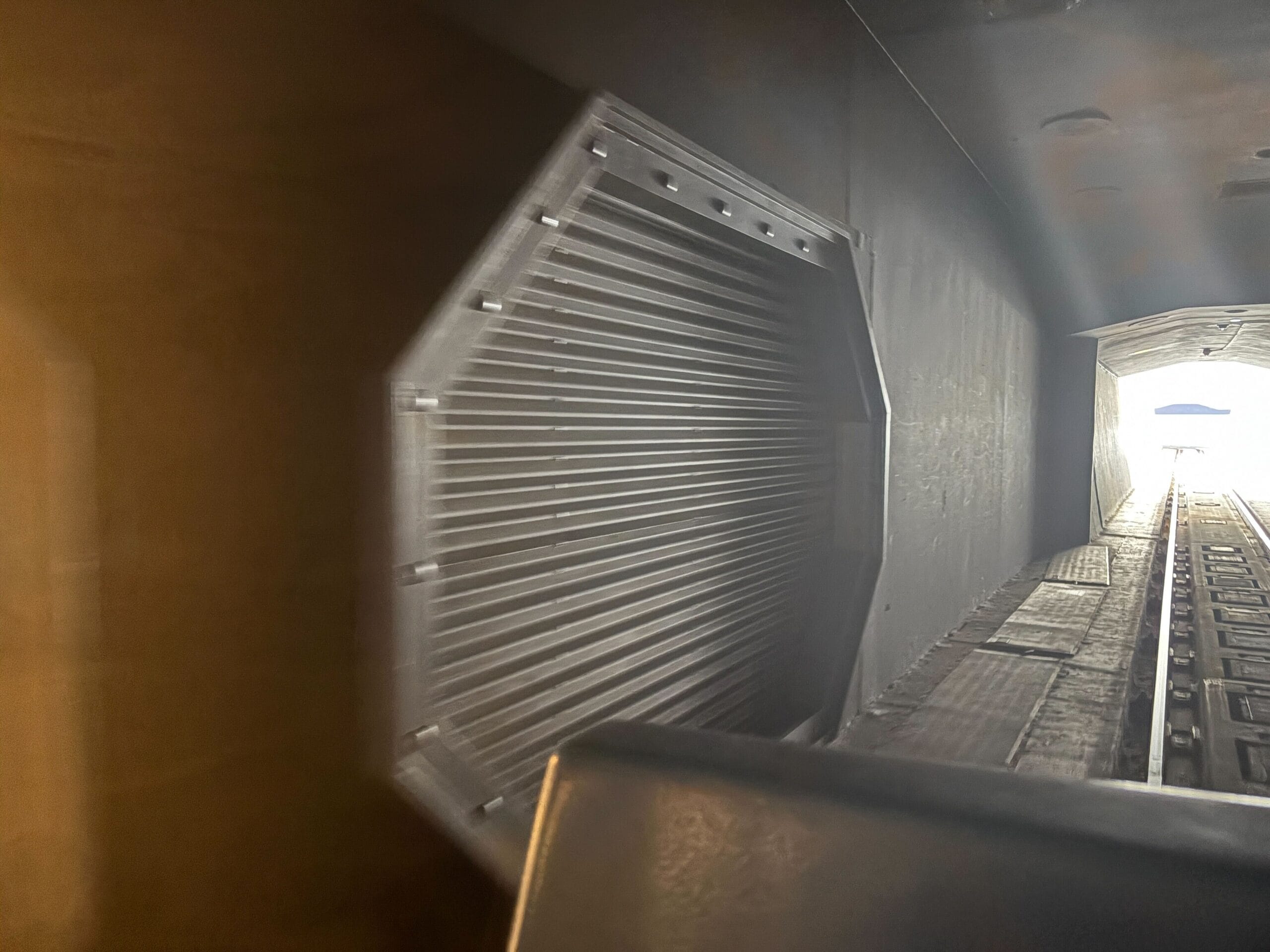 Buzz Lightyear Space Ranger Spin Closure - A close-up view of a metallic, octagonal door inside a dark tunnel with tracks leading toward a bright exit.