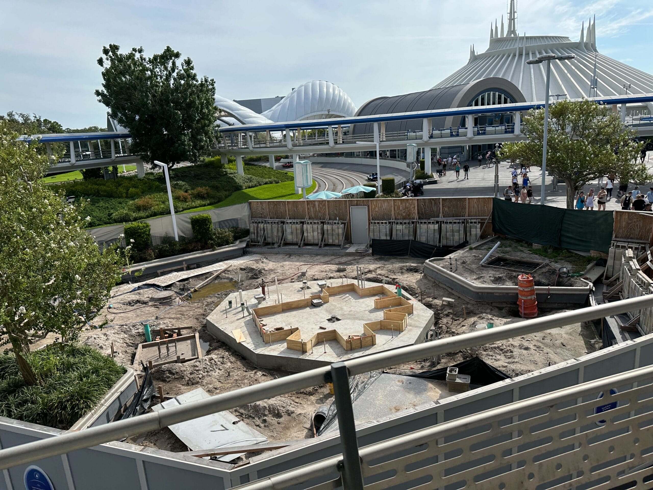 A construction site for the Cool Ship Update with a hexagonal foundation, near Space Mountain, fenced off with equipment.