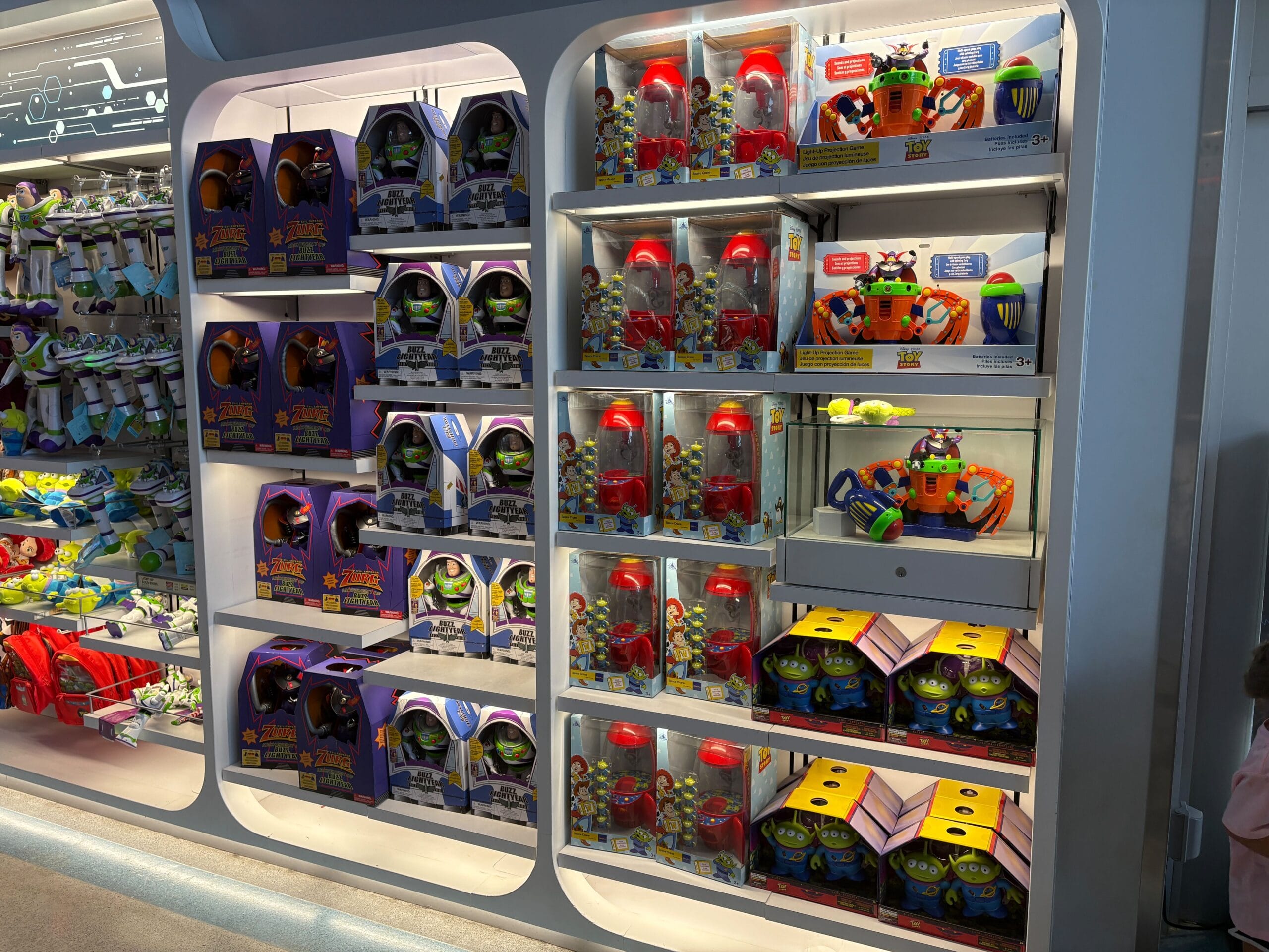 Store shelves display Toy Story Buzz Lightyear and alien toys in colorful boxes and packaging.