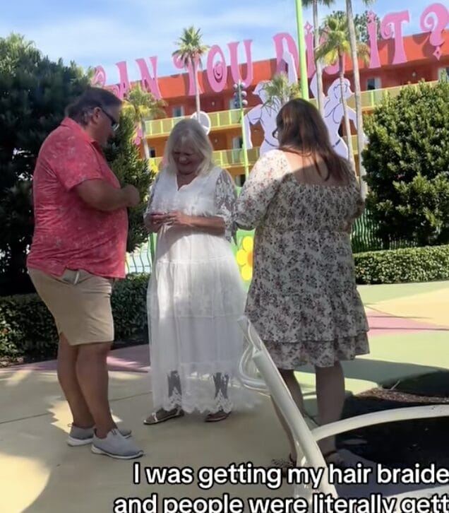 Three people stand together outdoors, smiling and talking near colorful buildings and palm trees at Pop Century.