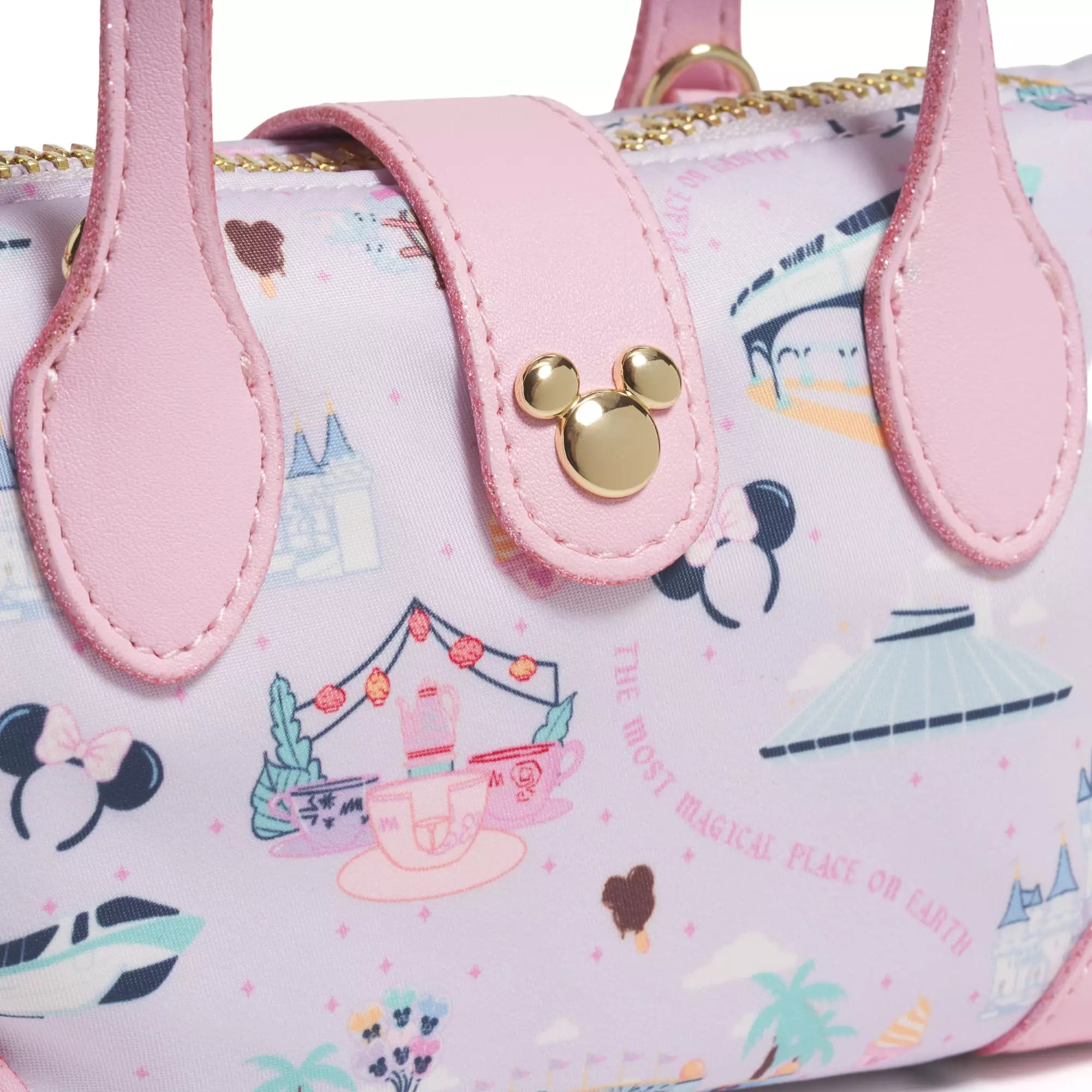 Close-up of a pink handbag with Disney-themed icons and a gold Mickey Mouse emblem on the strap.