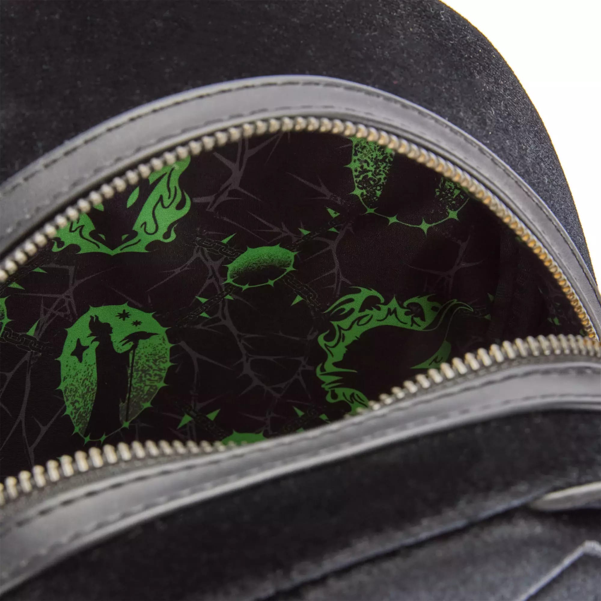 Open black bag reveals green and black lining with abstract Disney Villains-themed patterns inside.