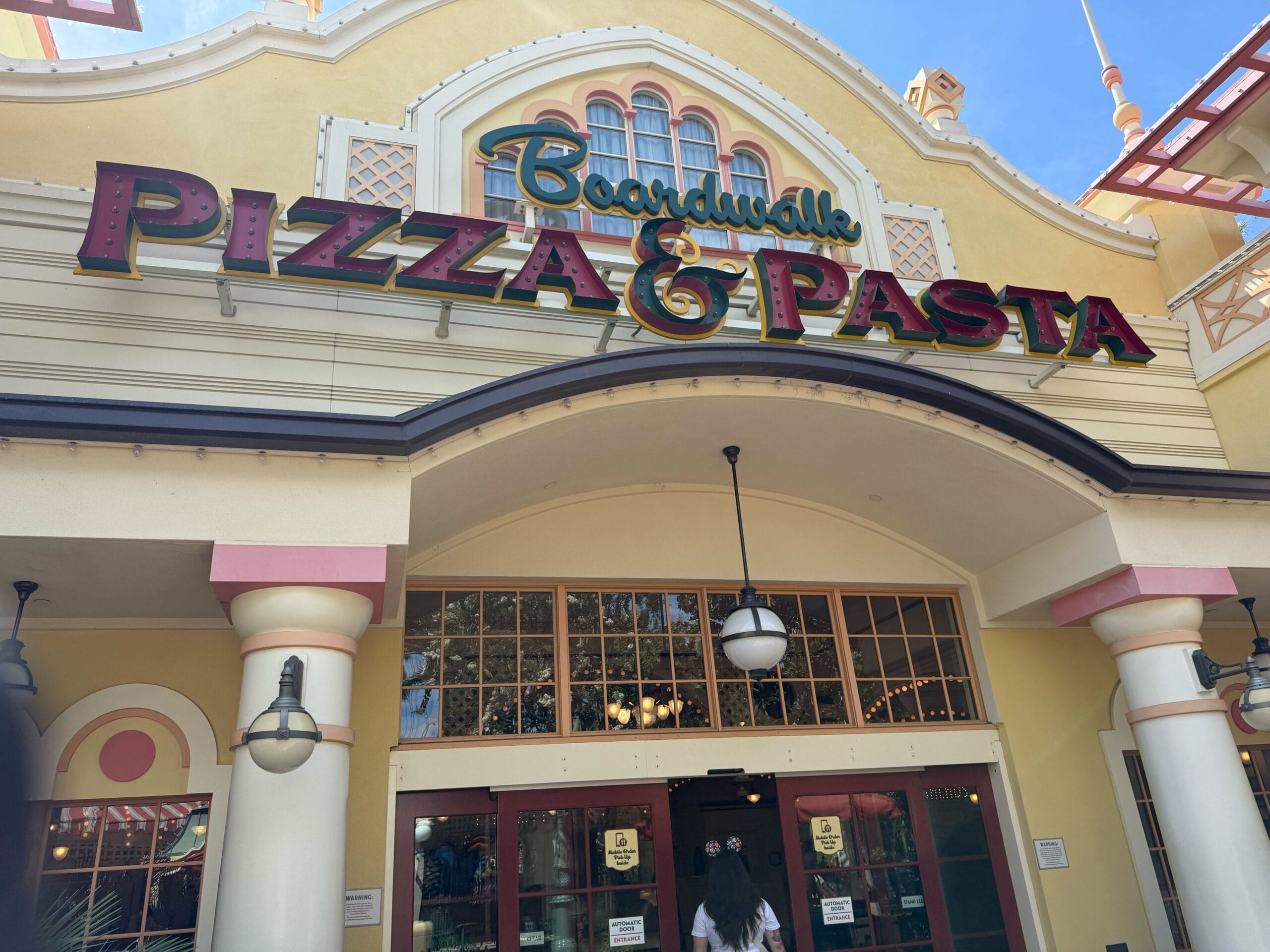 Entrance of BoardWalk Pizza & Pasta restaurant with large sign and pizza-themed decorative lights above the doorway.