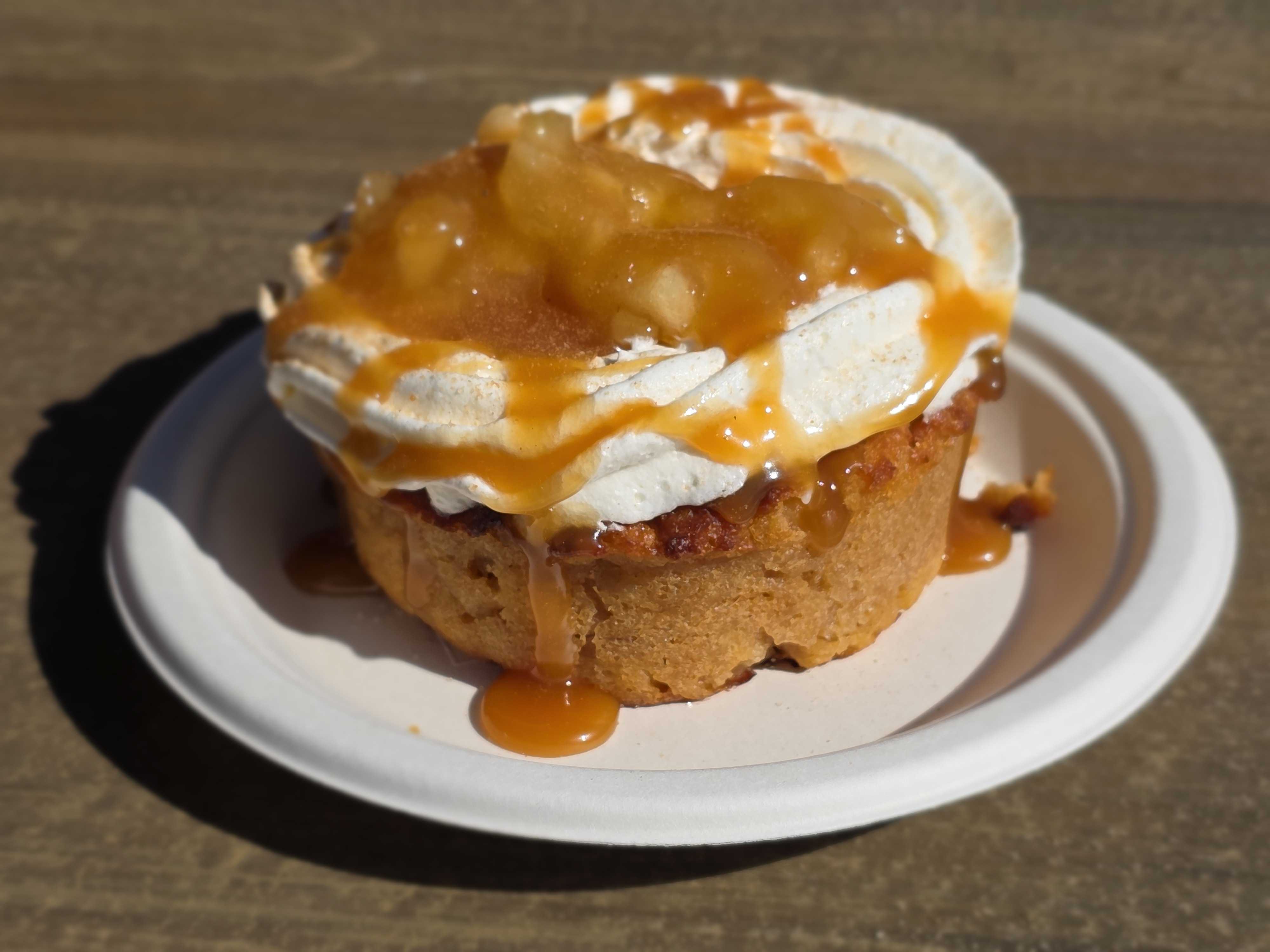 Aunt Cass Cafe’s caramel-drizzled dessert tart with whipped cream and fruit topping on a white plate.