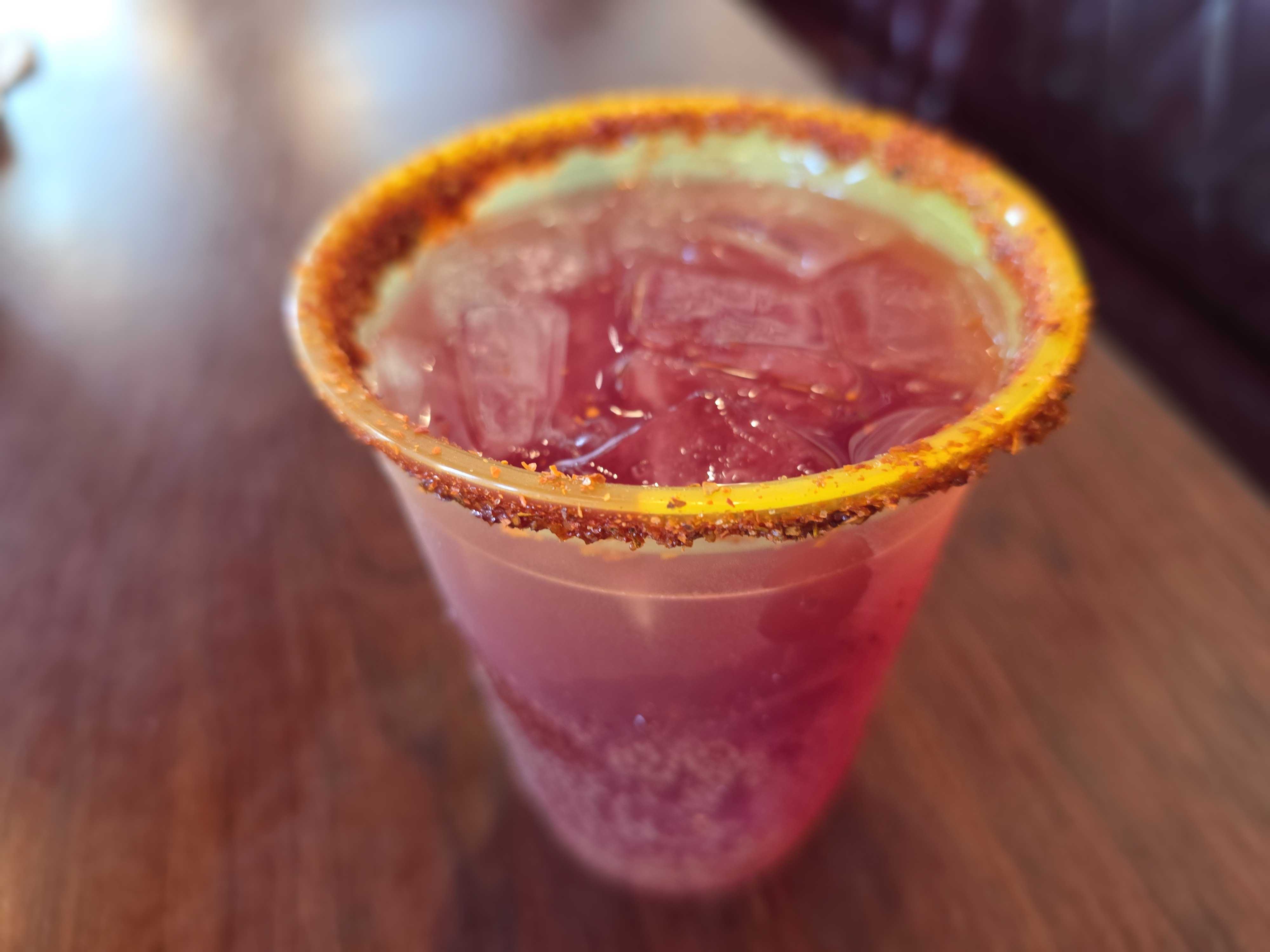 A cold Blackberry Margarita with chili powder rim sits on a wooden table at Flo's V8 Cafe.