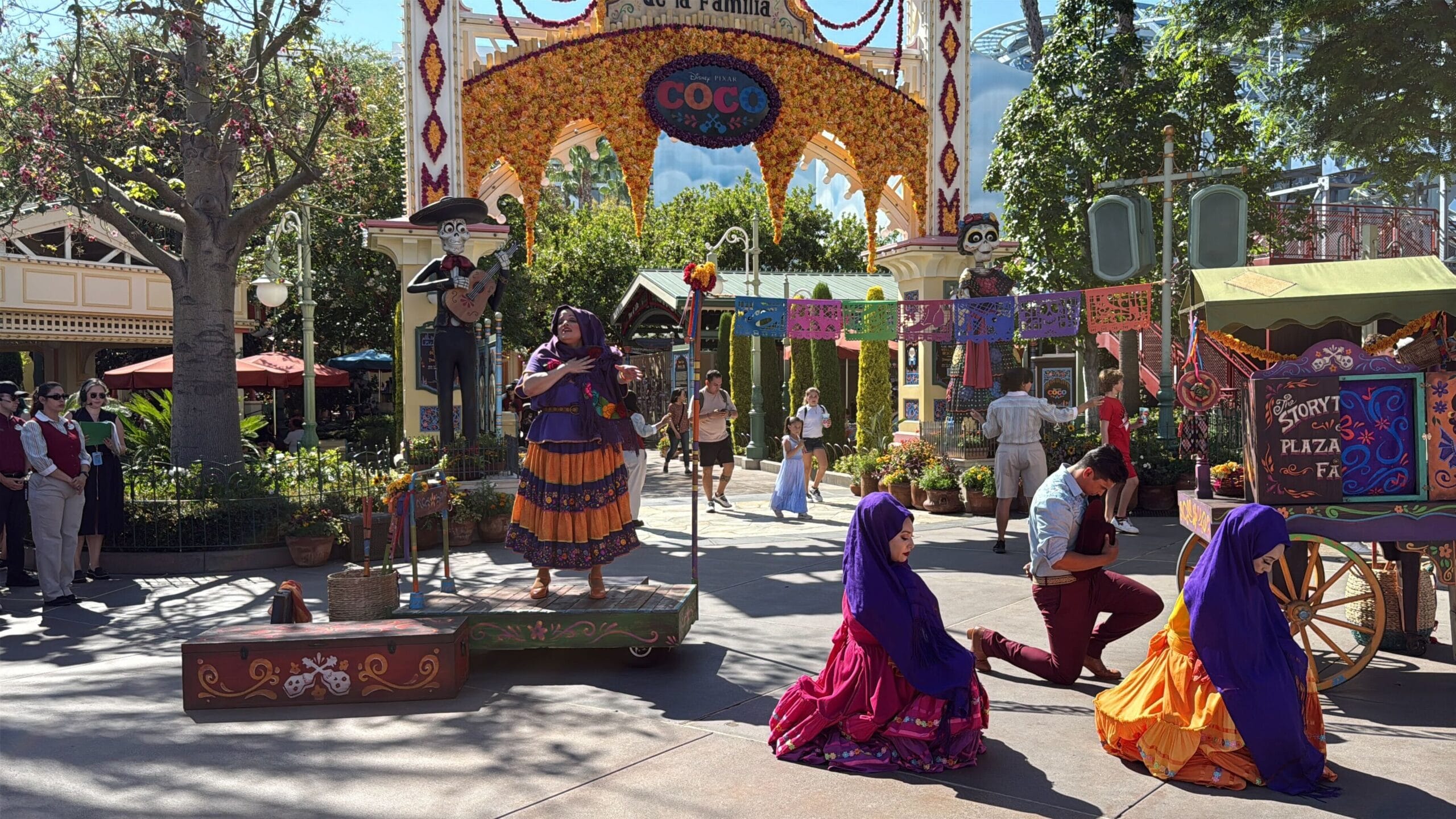 Performers in colorful costumes dance and play music at Plaza de la Familia during Celebrate Coco in Disney California Adventure.