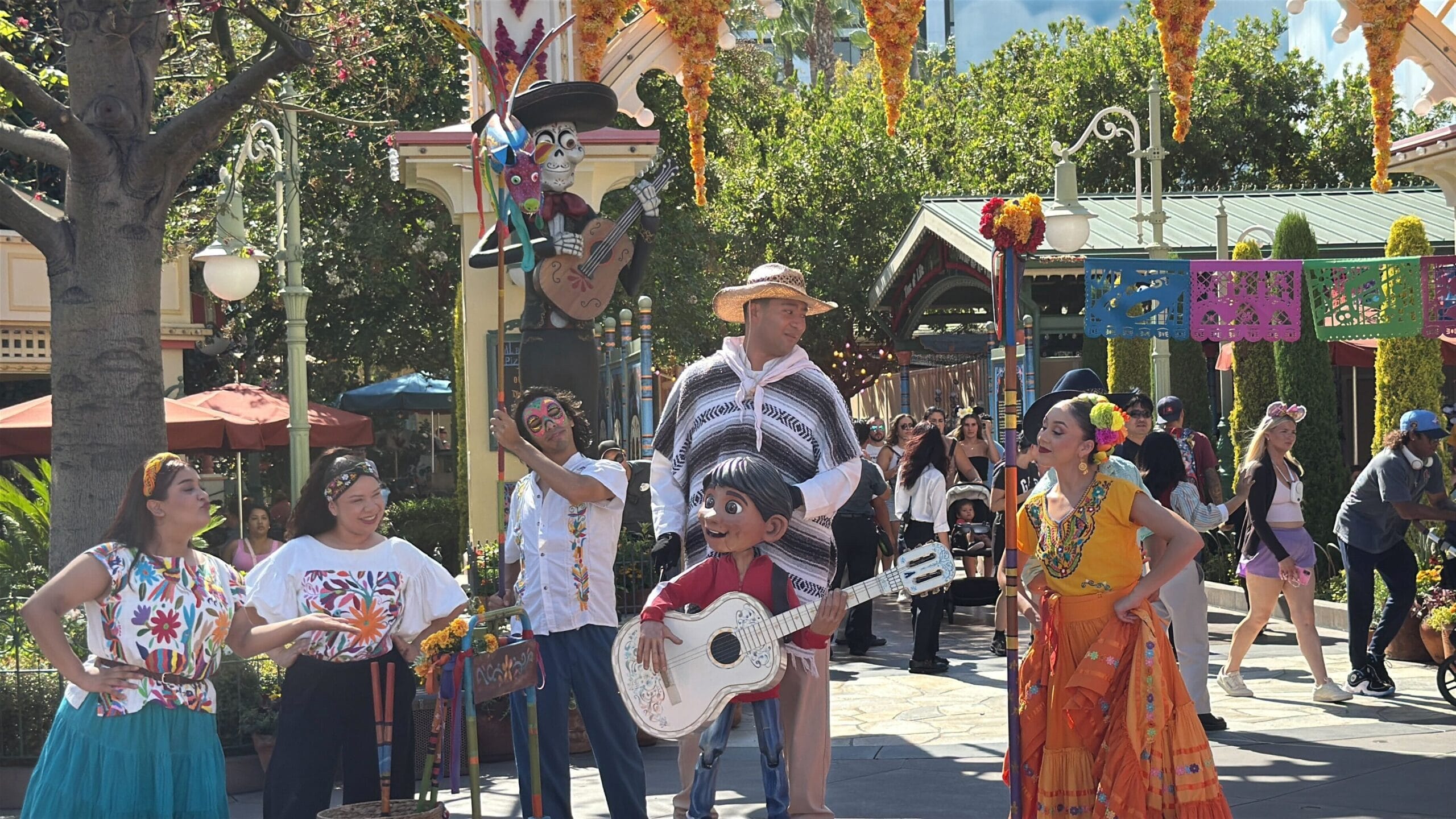 Five performers in colorful costumes, inspired by Coco, entertain guests at Plaza de la Familia in Disney California Adventure.