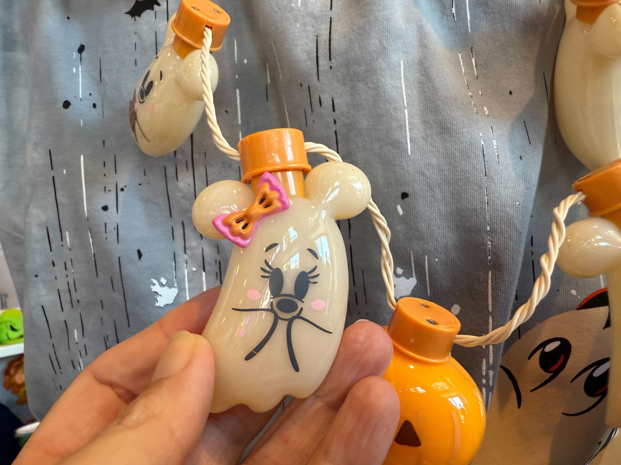 A hand holds a ghost-shaped Halloween light with an orange bow—perfect Halloween merchandise at Disneyland.