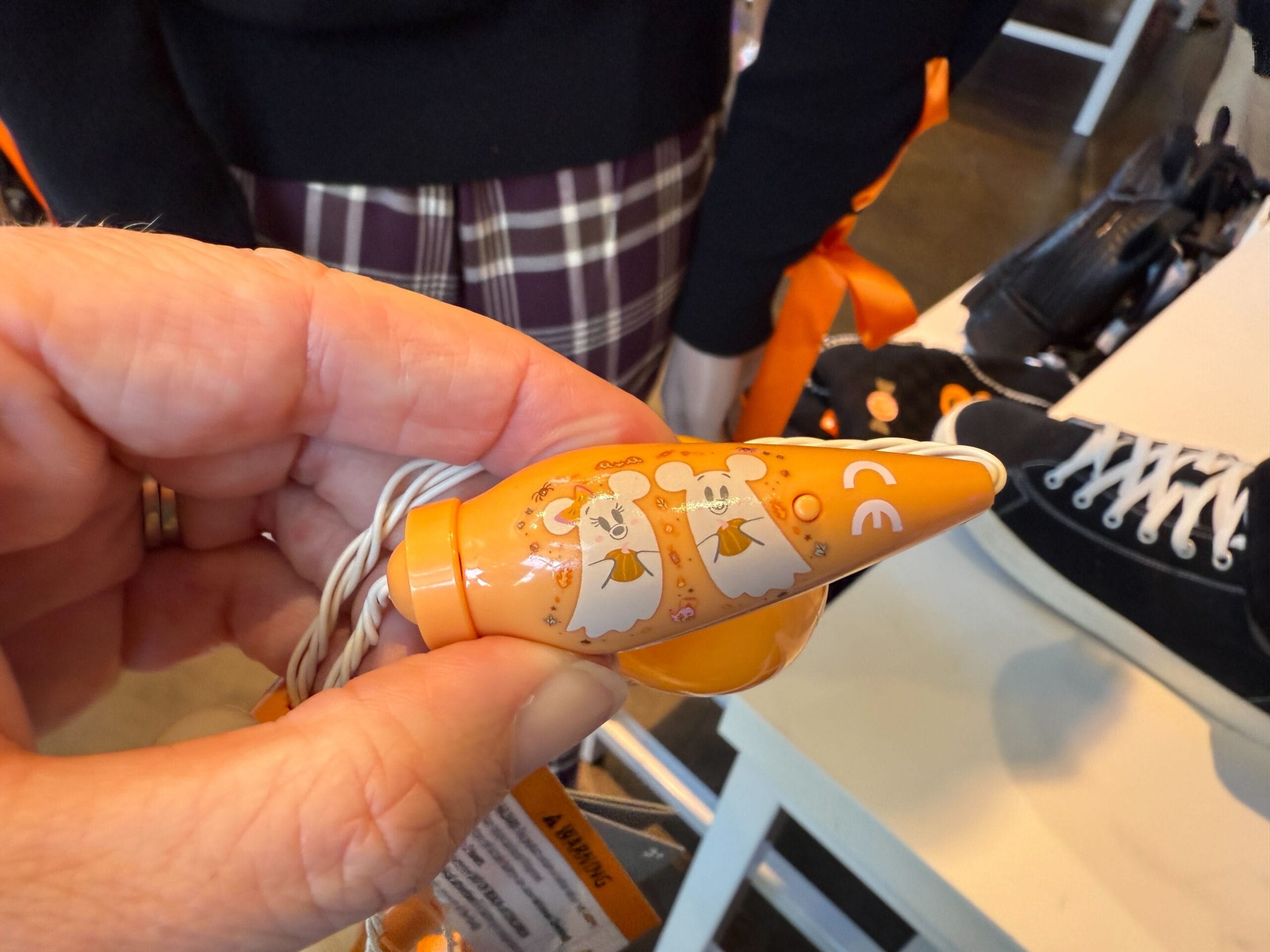 A hand holds an orange party blower from Disneyland, decorated with white mice in angel costumes.