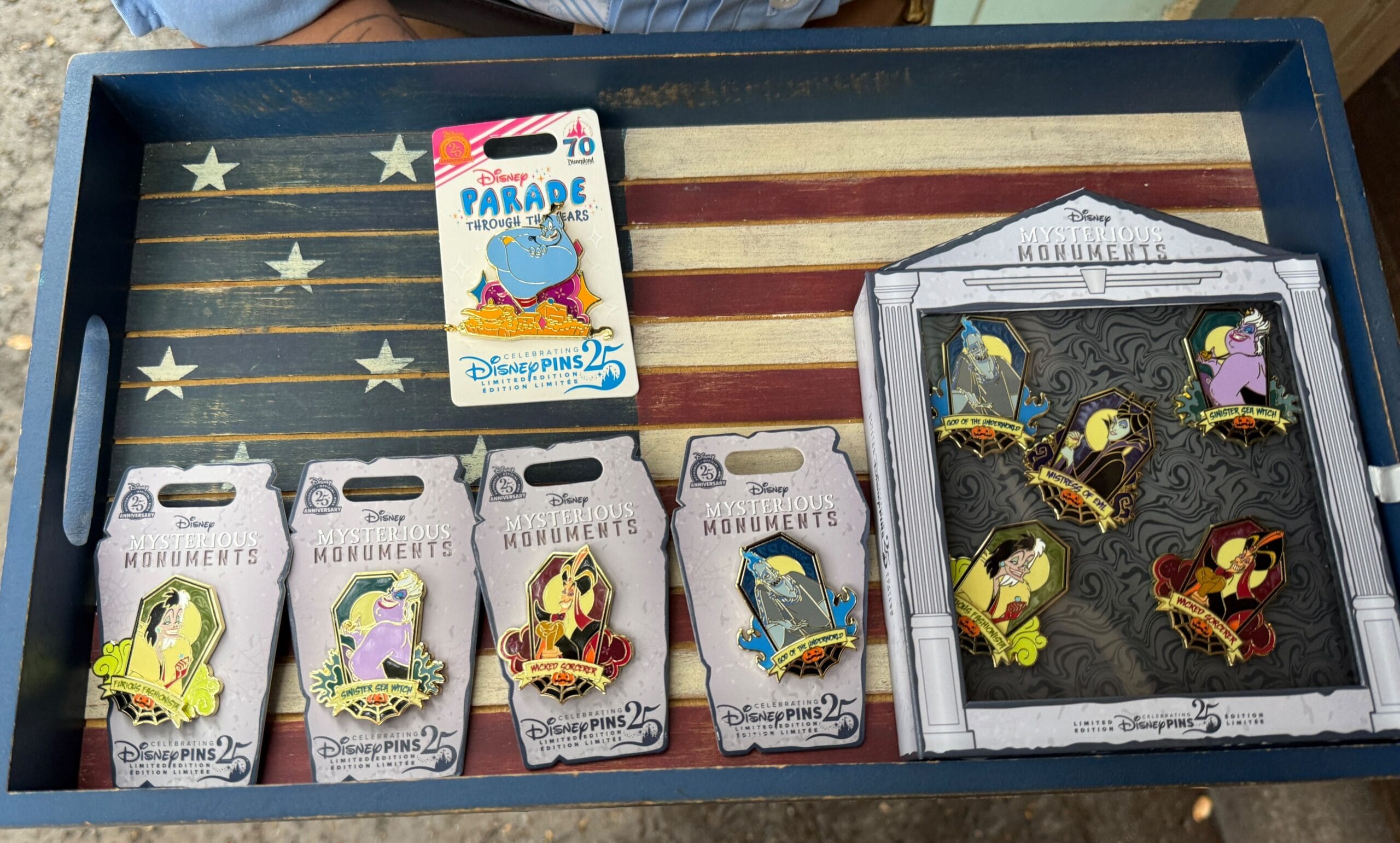 Disney Villains Pins displayed on an American flag tray, featuring "Mysterious Monuments" packaging from Disneyland Resort.