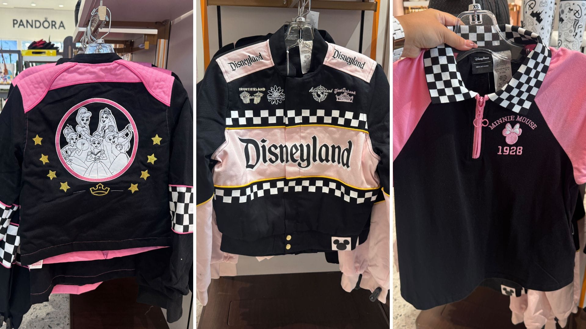 Three Disneyland-themed racer shirts in pink, black, and checkered patterns are displayed on hangers in a store.