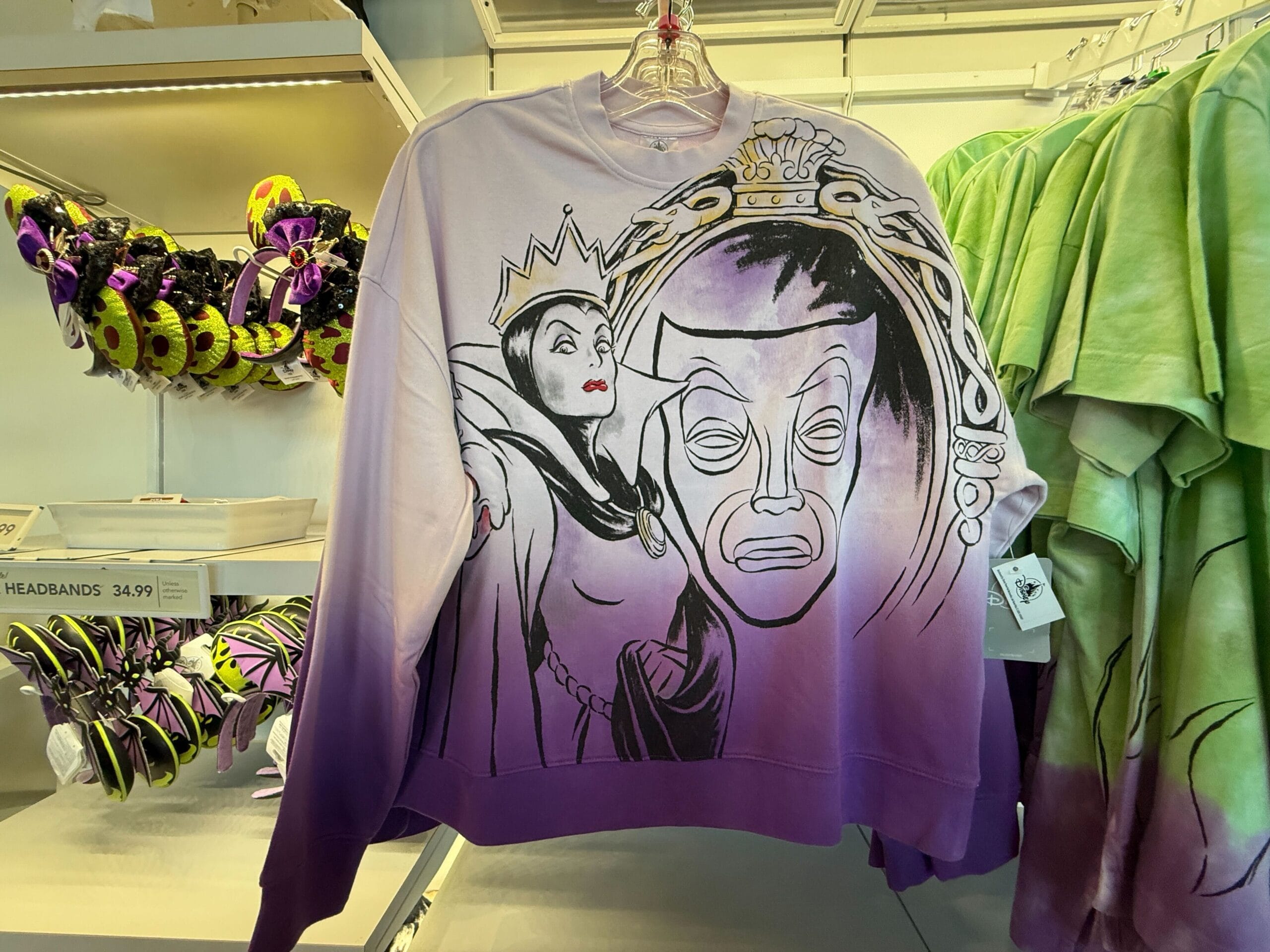 A purple ombre sweatshirt from Villains Apparel features the Evil Queen and magic mirror at Disneyland Resort.