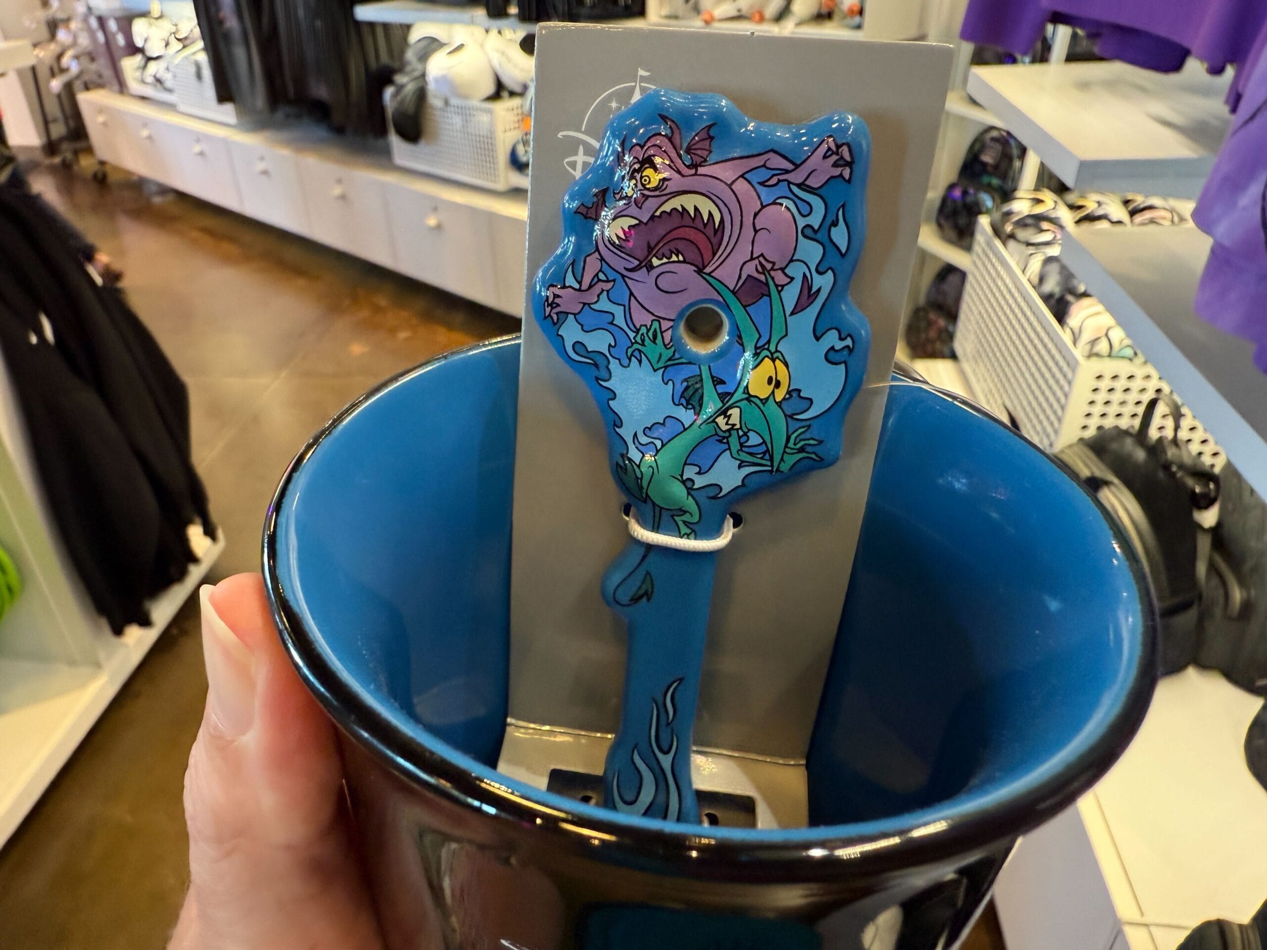 A hand holding a blue cup with a cartoon design, perfect for fans of Villains Merchandise.