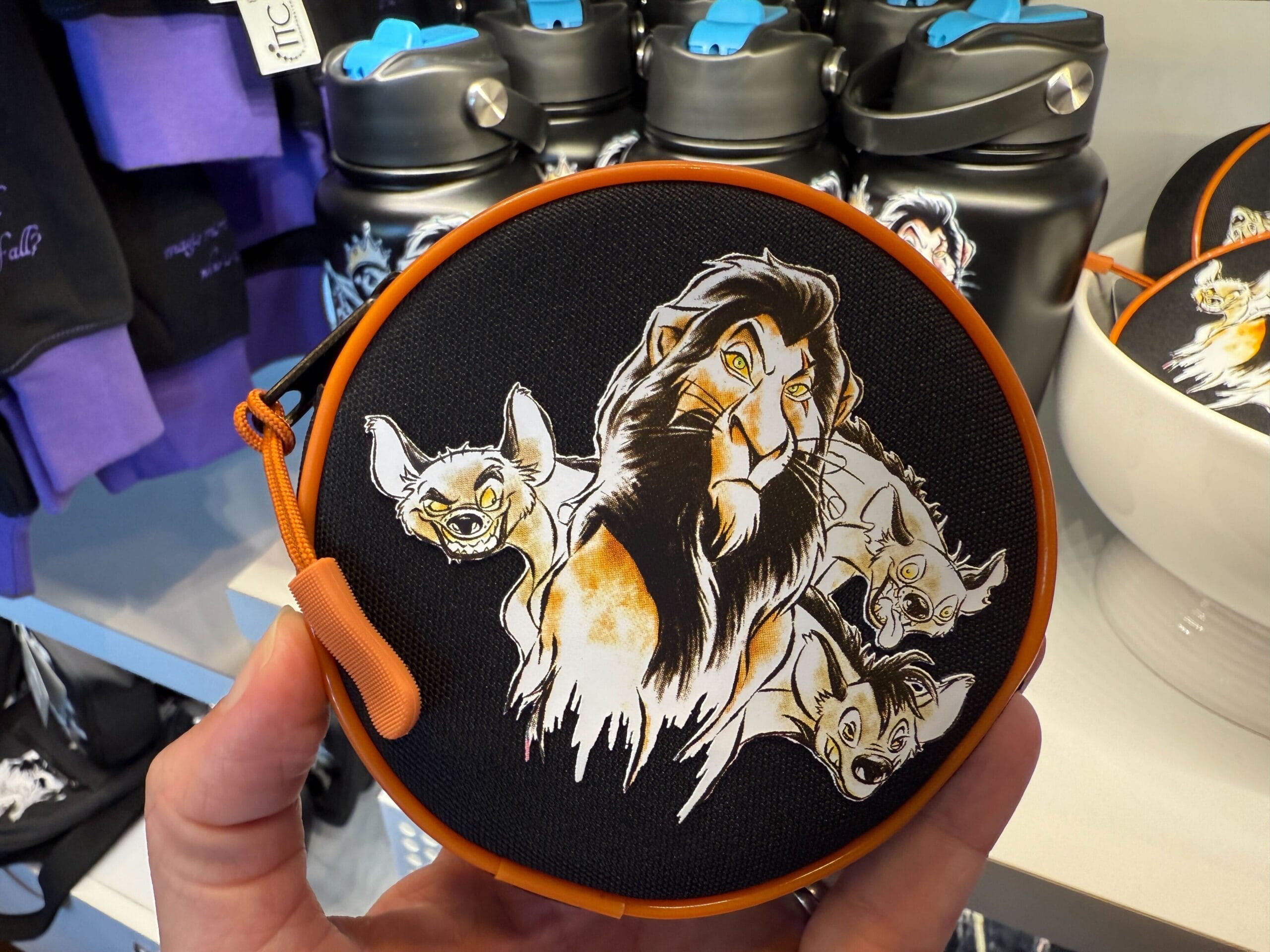 Round bag with Lion King’s Scar and hyenas, held in hand at a store—perfect Villains apparel merchandise.