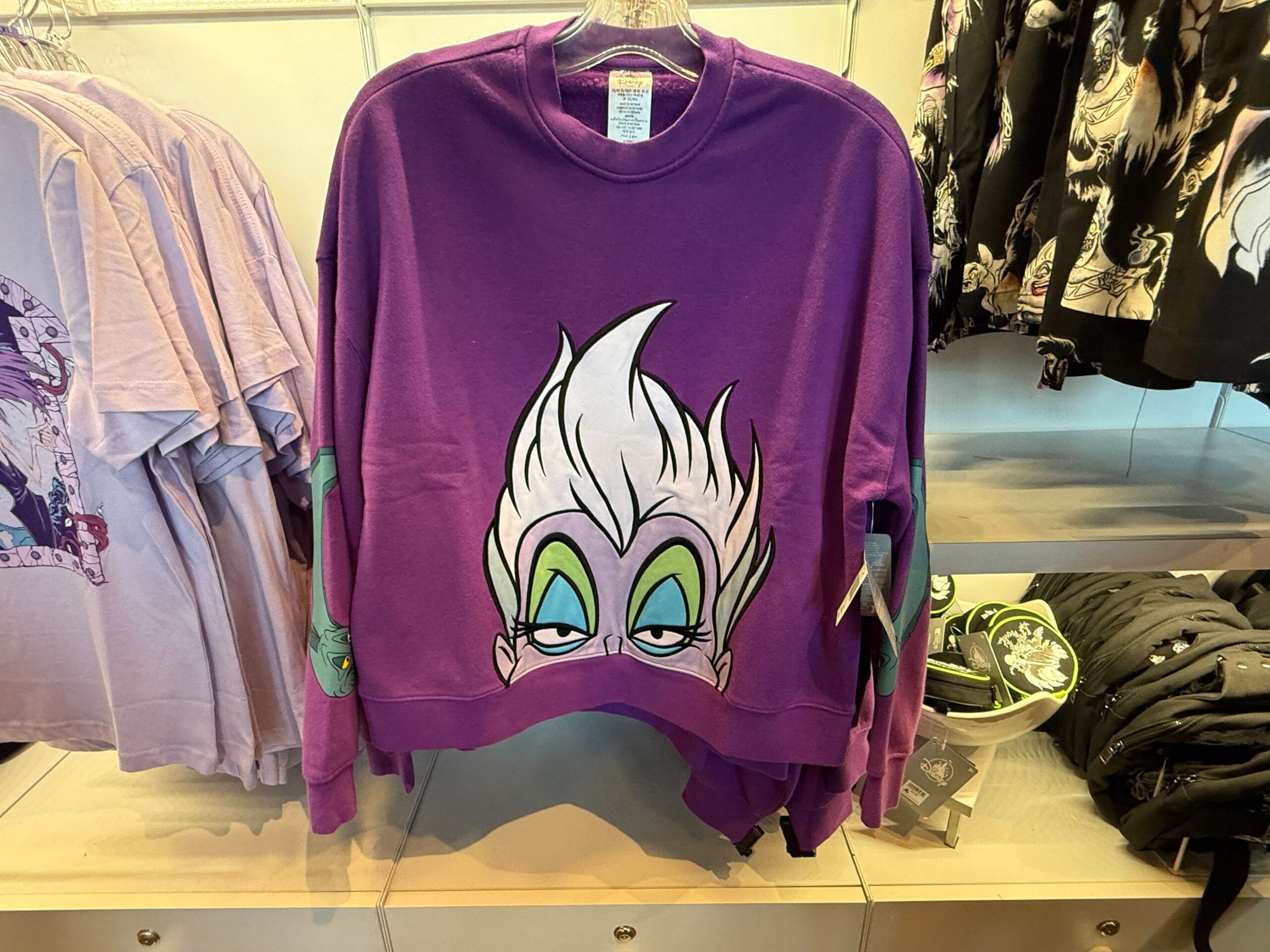 Purple sweatshirt featuring a large cartoon face, perfect Villains apparel merchandise at the Disneyland Resort store rack.