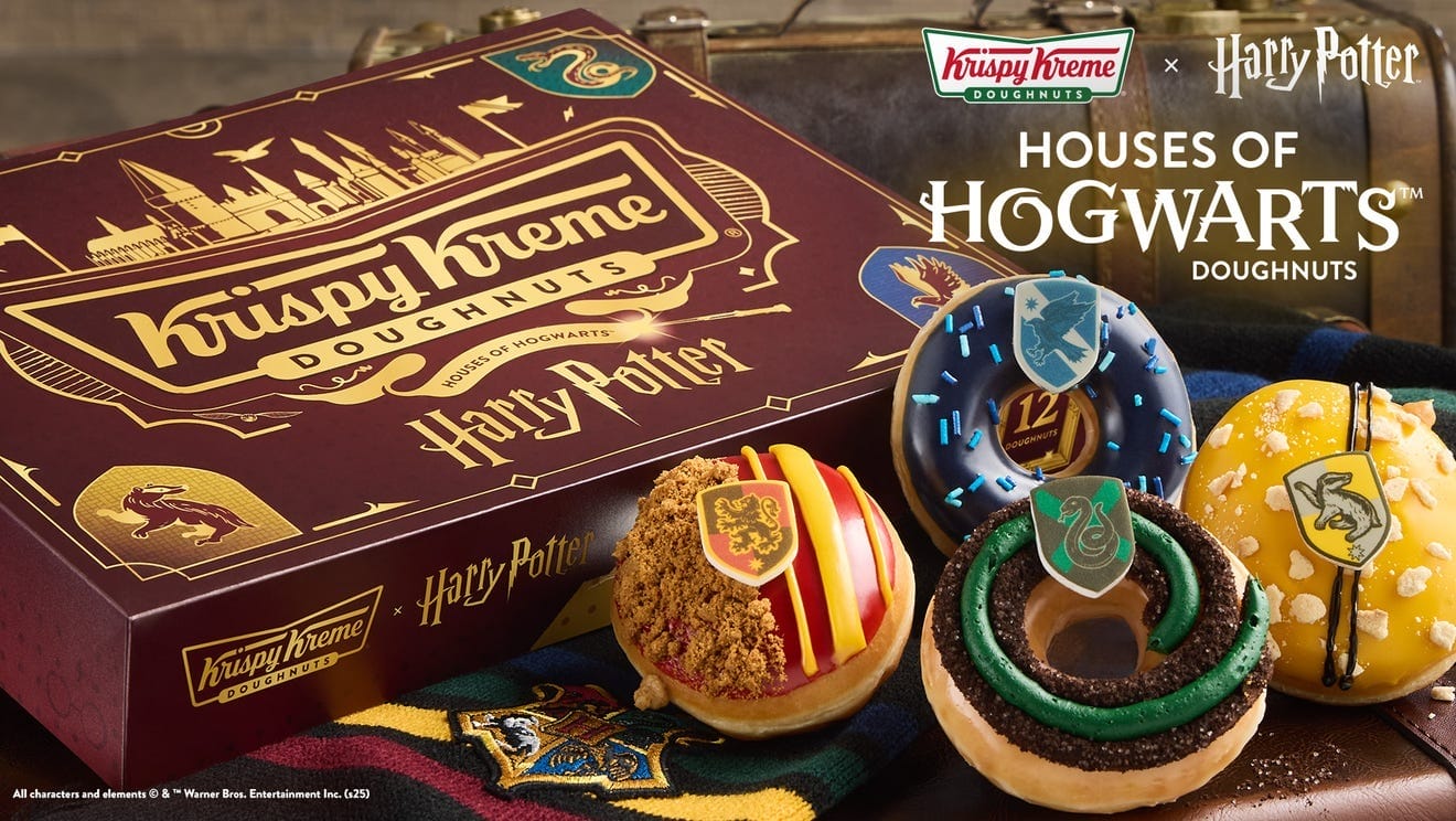 A Krispy Kreme Harry Potter box featuring four magical Hogwarts house doughnuts displayed in front.
