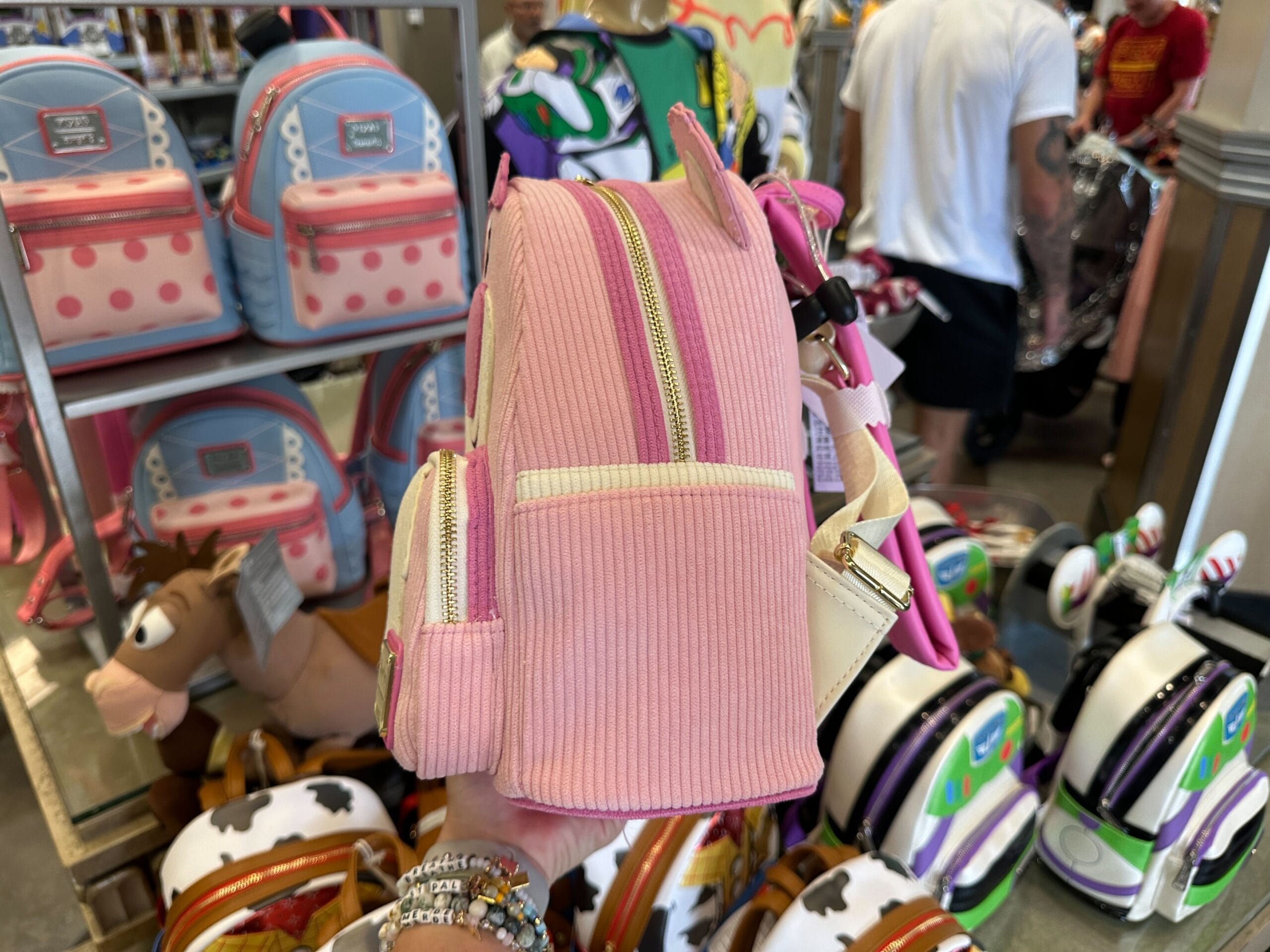 A scented Lotso Loungefly Backpack at a store in Disney's Hollywood Studios, surrounded by colorful bags.