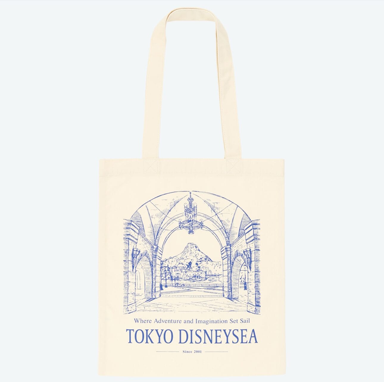 Cream tote bag with a blue line drawing of Tokyo Disney Resort, featuring Mount Prometheus and park entrance arches.