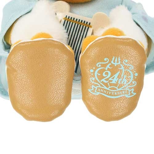 Close-up of a plush toy's brown feet, with "24th Anniversary" and a trident design printed on the right foot.