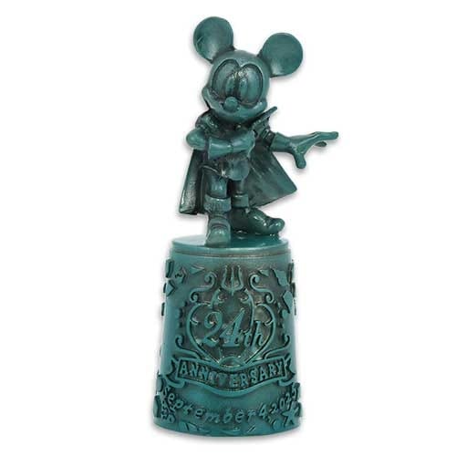 A green figurine of Mickey Mouse in a cape stands on a decorated base marked "24th ANNIVERSARY November 2022.