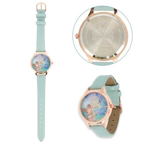 A pastel blue wristwatch with a gold case and an illustrated dial featuring a mermaid and the sea.