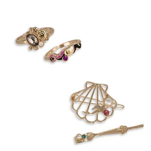 Two decorative rings, a gold seashell-shaped brooch, and a gold wand-shaped brooch with colorful stones and pearls.