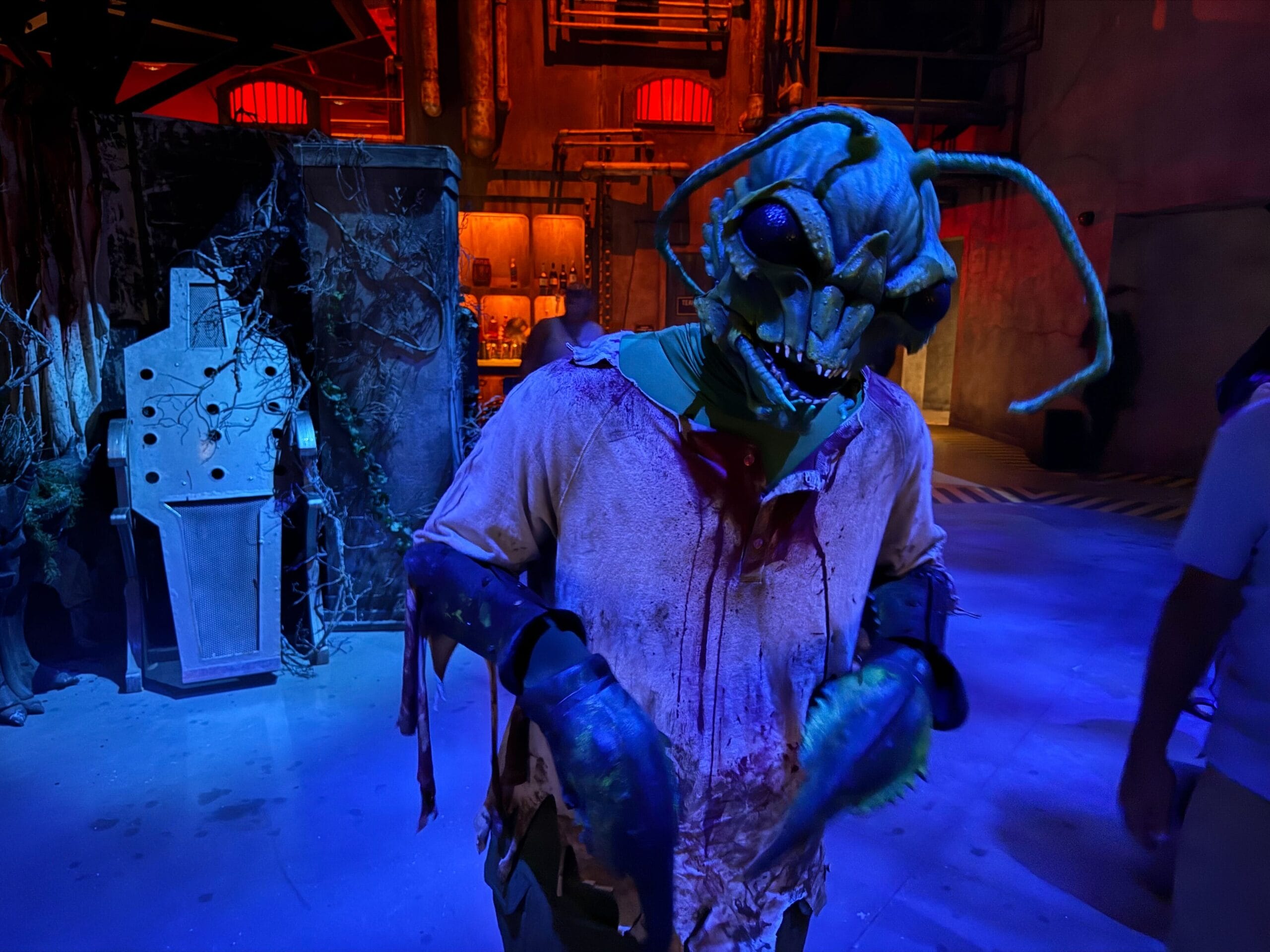 Person in a detailed insect monster costume stands in a dim, eerie setting at Universal Horror Unleashed Las Vegas.