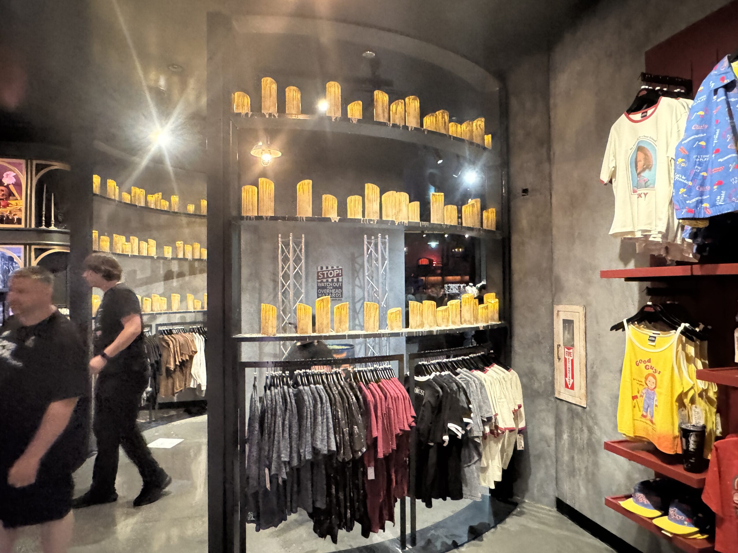 Clothes hang below shelves lined with yellow corn props in a Universal Horror Unleashed Las Vegas themed retail store.