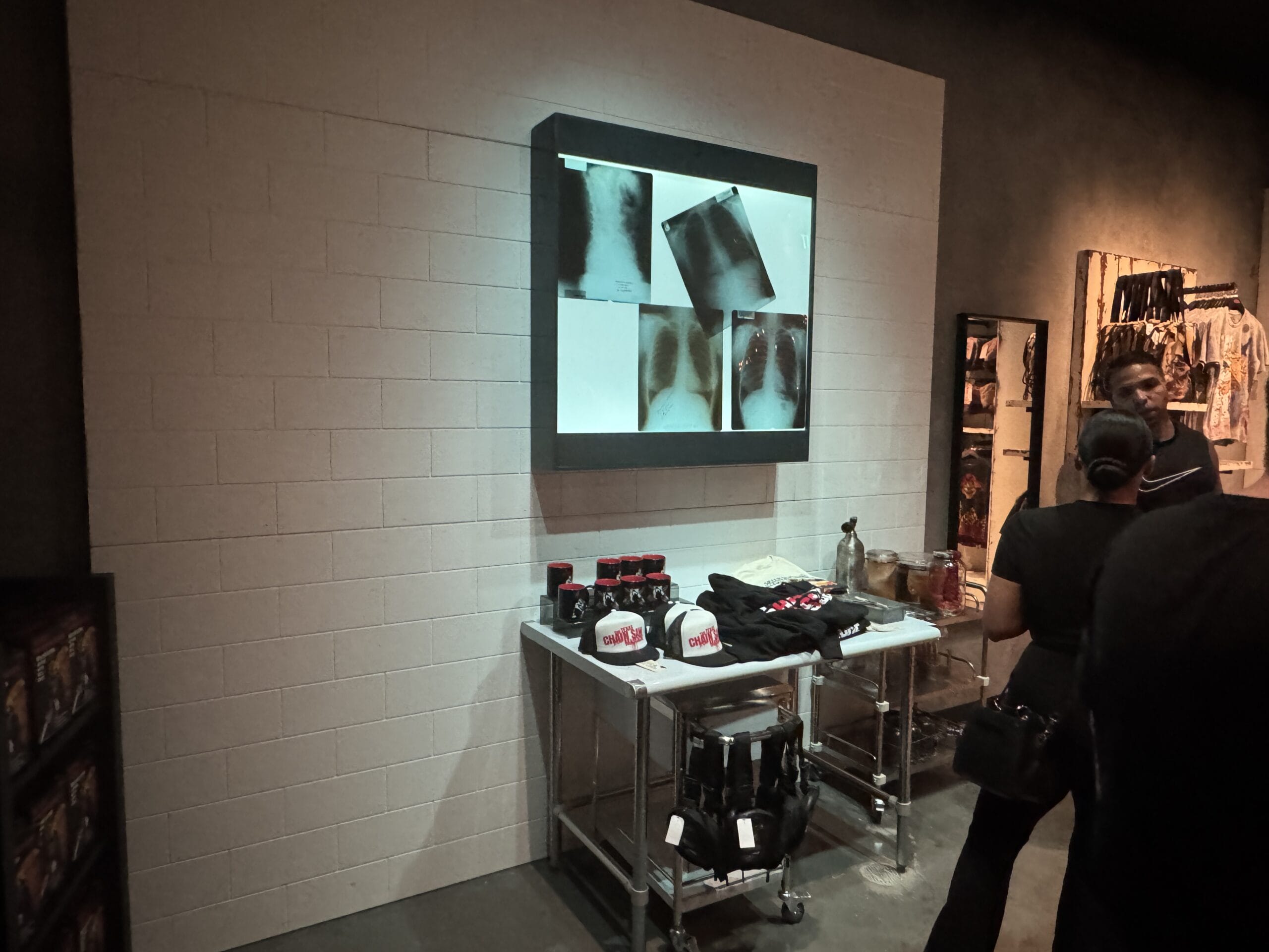 A display table with hats and accessories beneath X-ray images at Universal Horror Unleashed in dimly lit Las Vegas store.