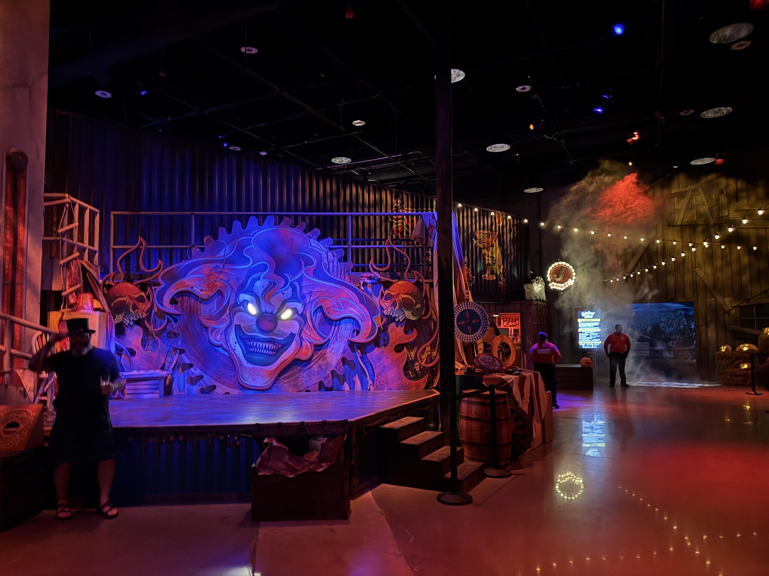 Dimly lit Las Vegas carnival-themed room with creepy clown mural, stage, and props from Universal Horror Unleashed Full Tour.