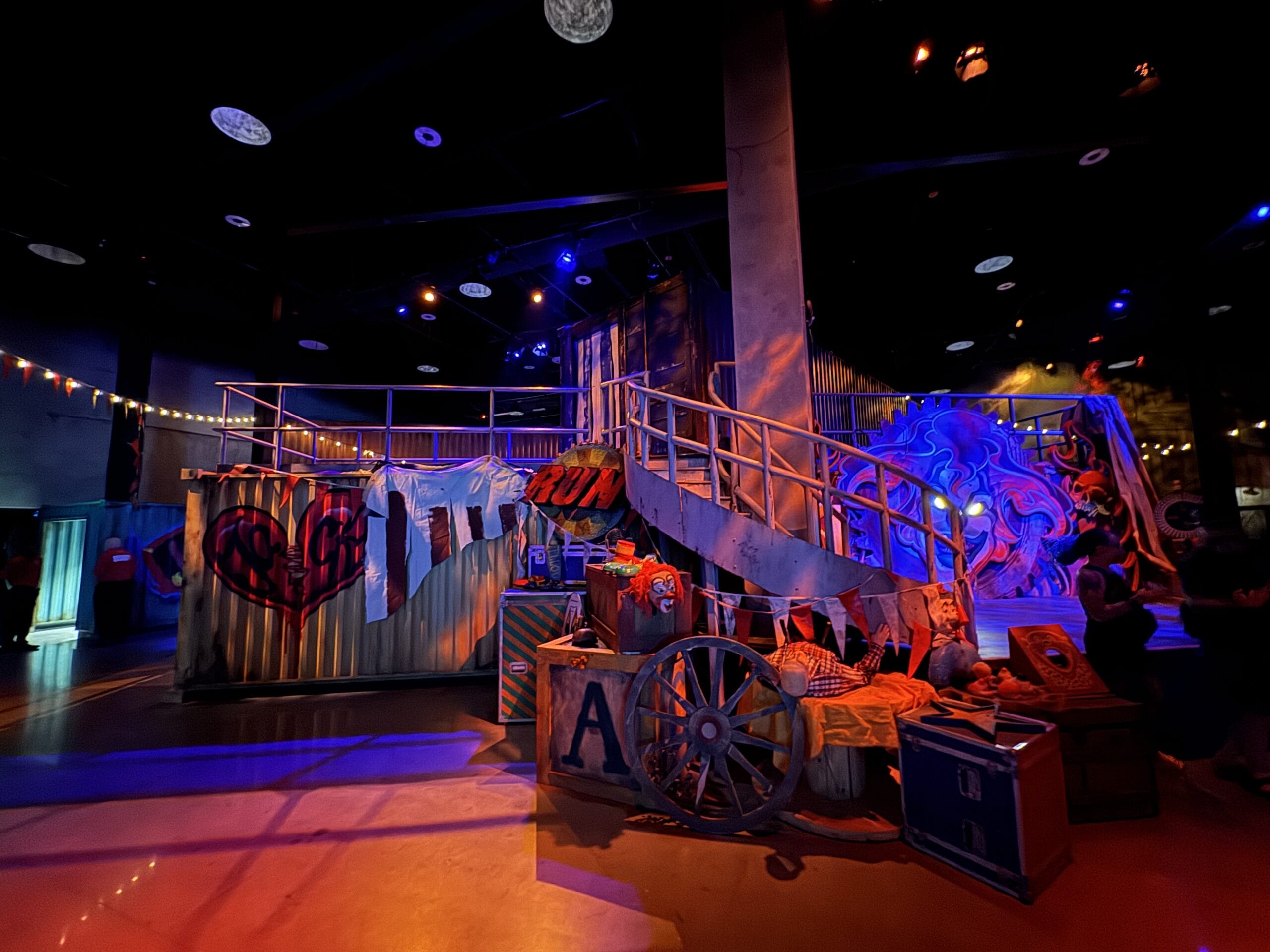 Colorful indoor carnival scene with bunting, a ramp, and circus decor—like a Las Vegas full tour under dramatic lighting.