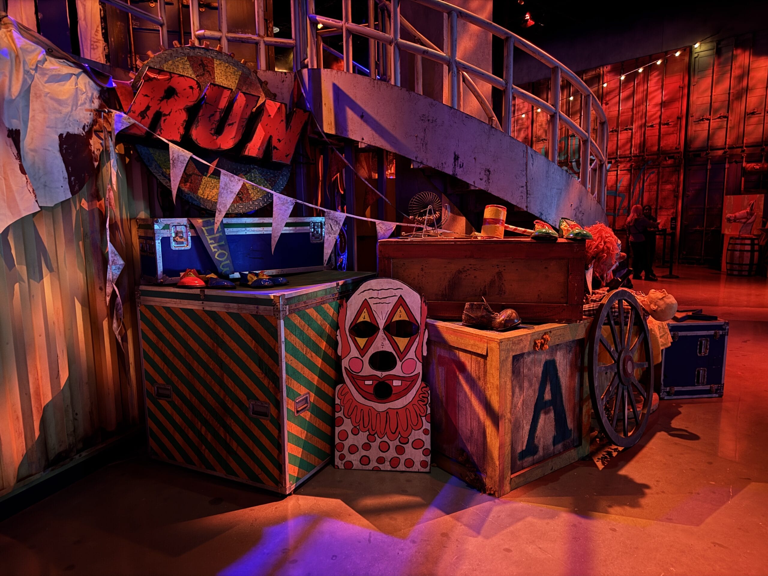 A circus-themed set in Las Vegas with colorful trunks, a "RUN" sign, and Universal Horror Unleashed red lighting.