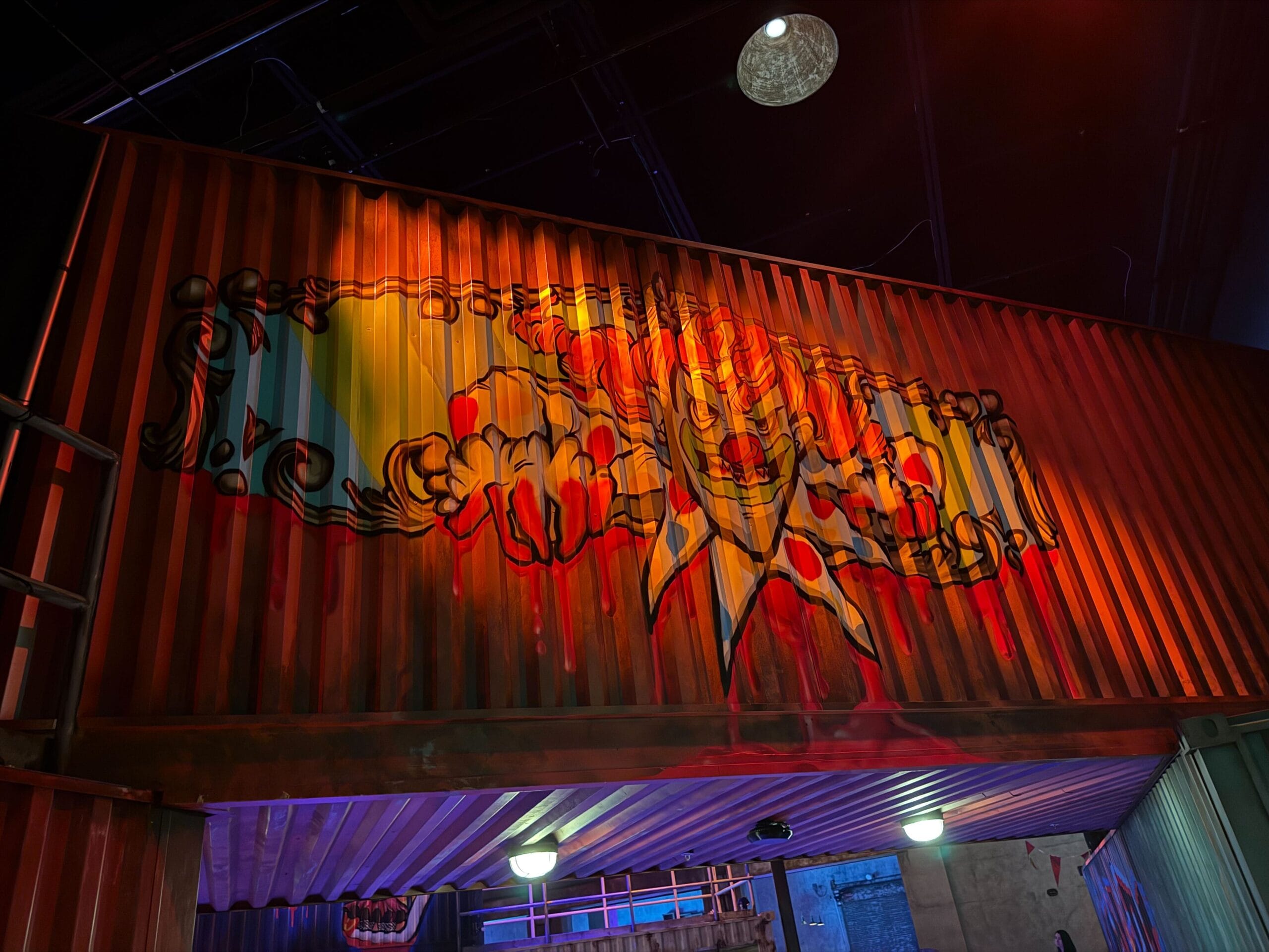A creepy clown face mural glows under dramatic lighting at Universal Horror Unleashed in Las Vegas.