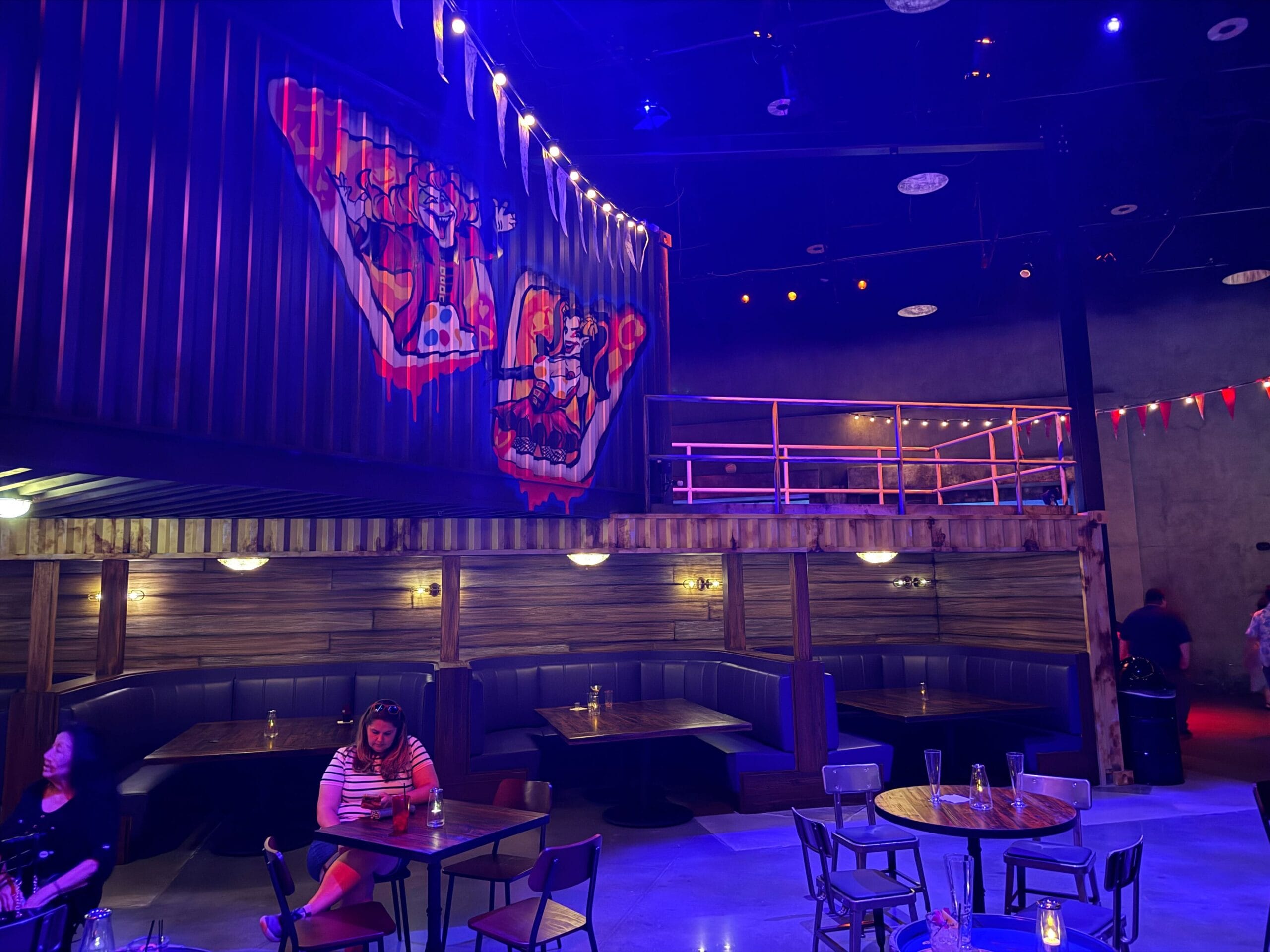 Colorful Las Vegas restaurant interior with clown mural, string lights, and booths—like a Universal Horror Unleashed full tour.