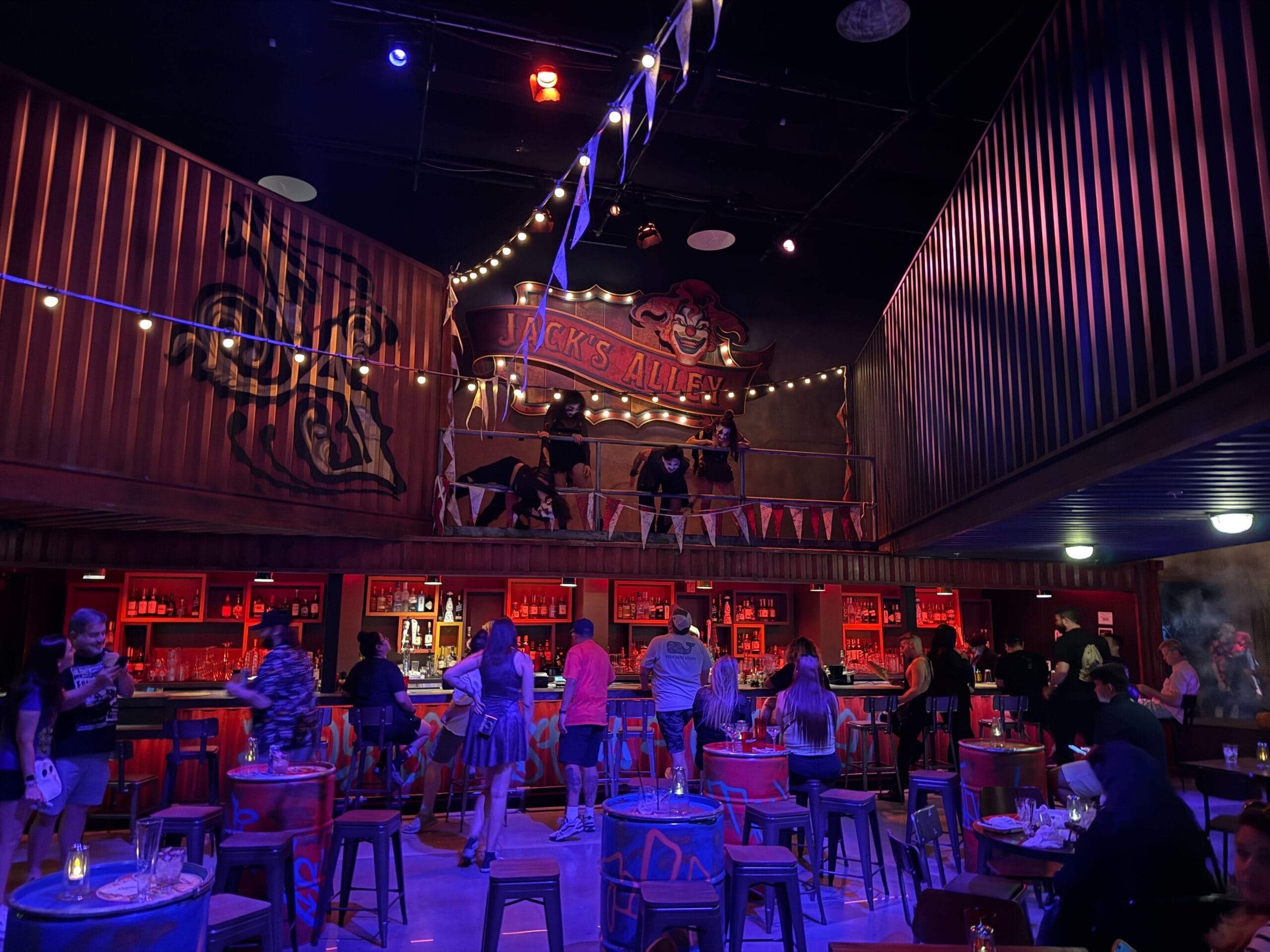 Bar with red lighting and performers on a balcony under string lights—like a Universal Horror Unleashed night in Las Vegas.