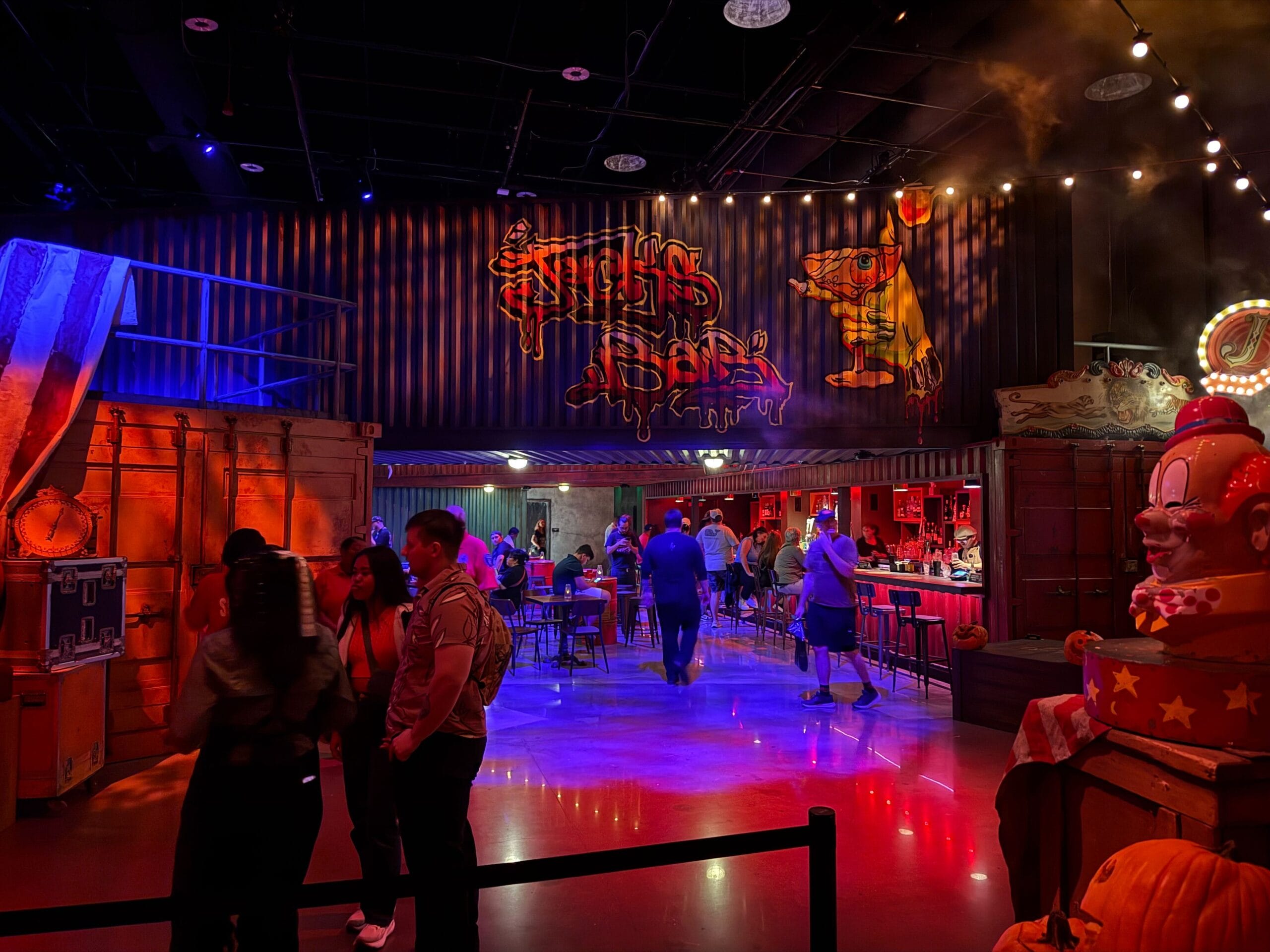 People walk inside a dimly lit, circus-themed bar in Las Vegas, featuring clown decor and a Universal Horror Unleashed vibe.