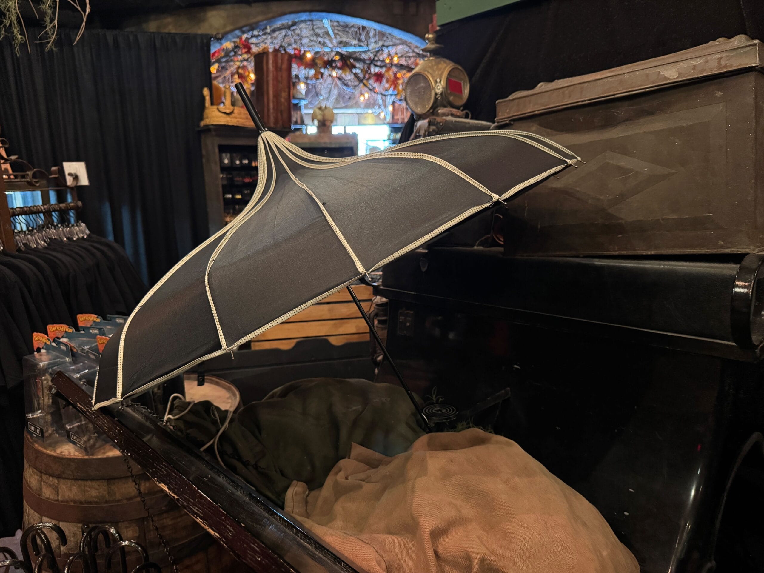 A black umbrella with white trim sits open on old fabrics inside a vintage vehicle in a dimly lit shop.