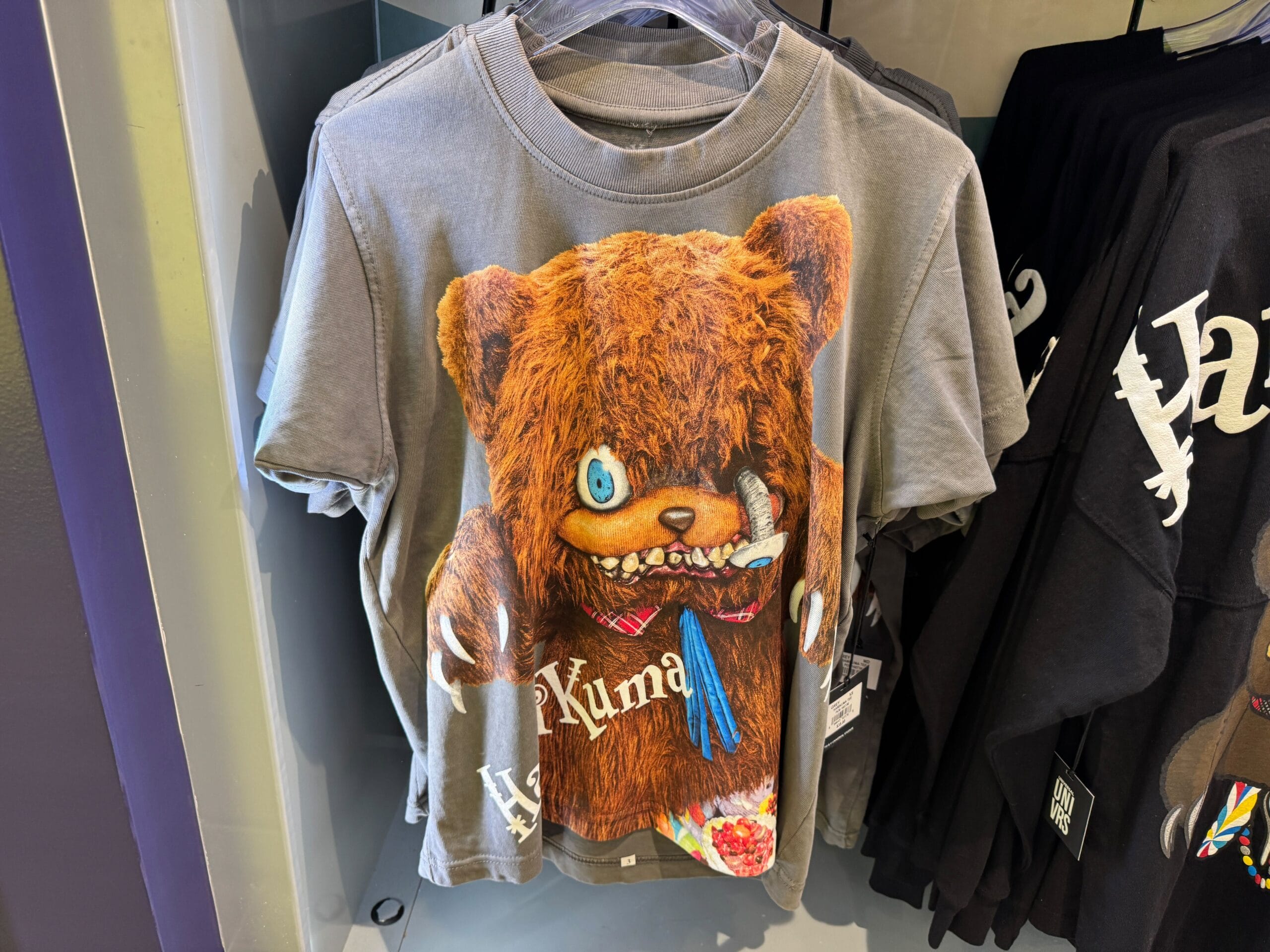 Gray t-shirt with a wild-eyed bear holding chopsticks and a bowl, labeled "Kuma"—perfect HHN Merch 2025 collectible.