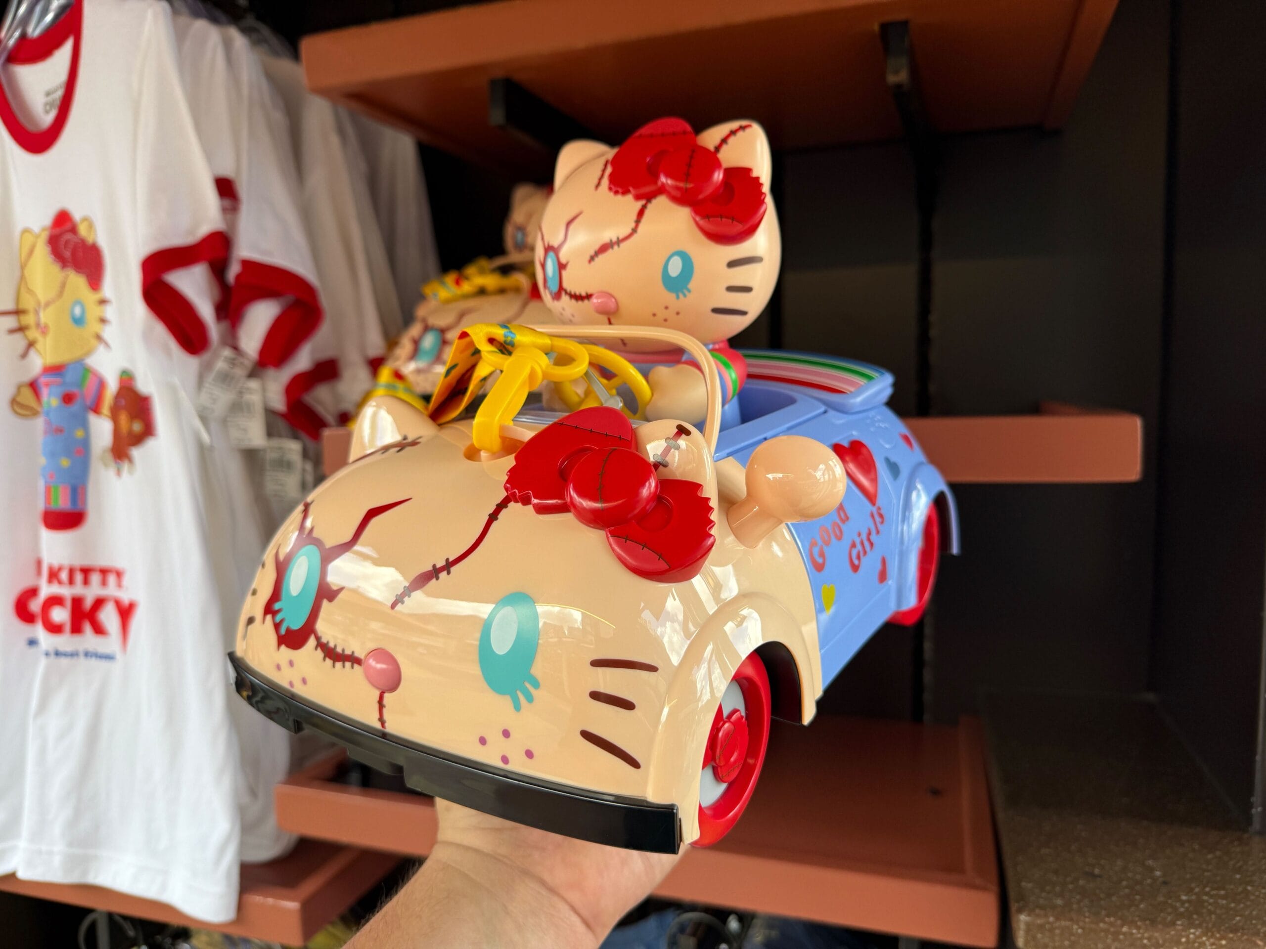 A hand holds a toy car featuring a spooky Hello Kitty figure, reminiscent of Universal Studios Florida collectibles.
