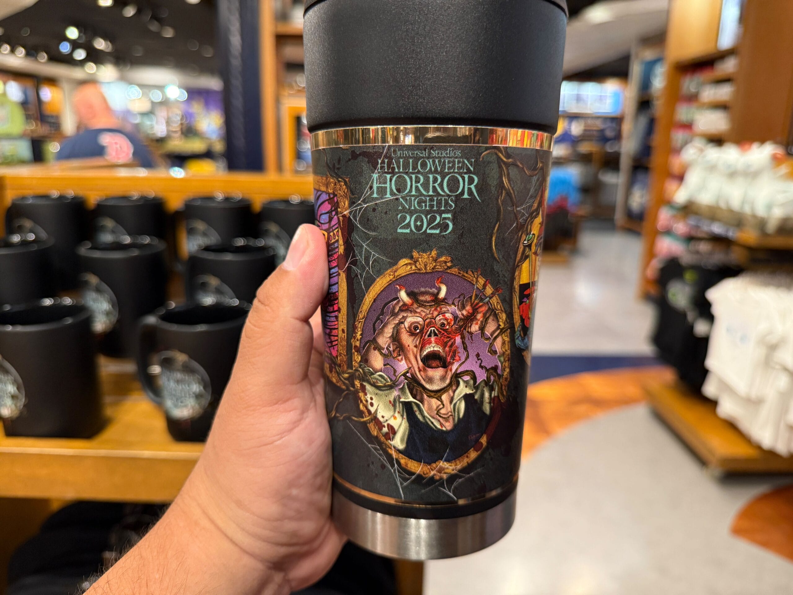A hand holds a "Halloween Horror Nights 2025" travel mug—spooky HHN Merch 2025 at Universal Orlando Resort.