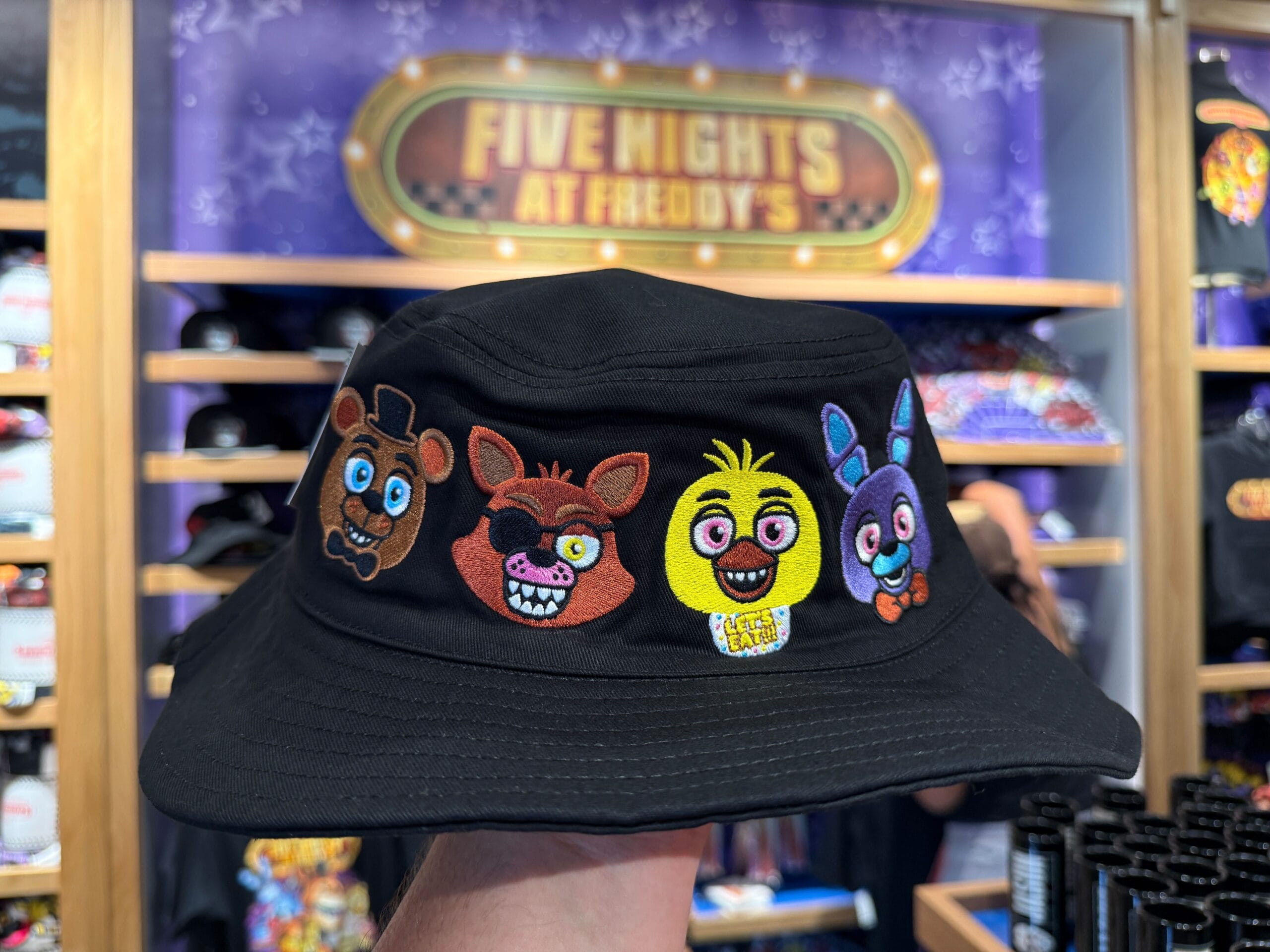 A black bucket hat with Four Five Nights at Freddy's, exclusive HHN merch at a themed Universal Orlando Resort store.