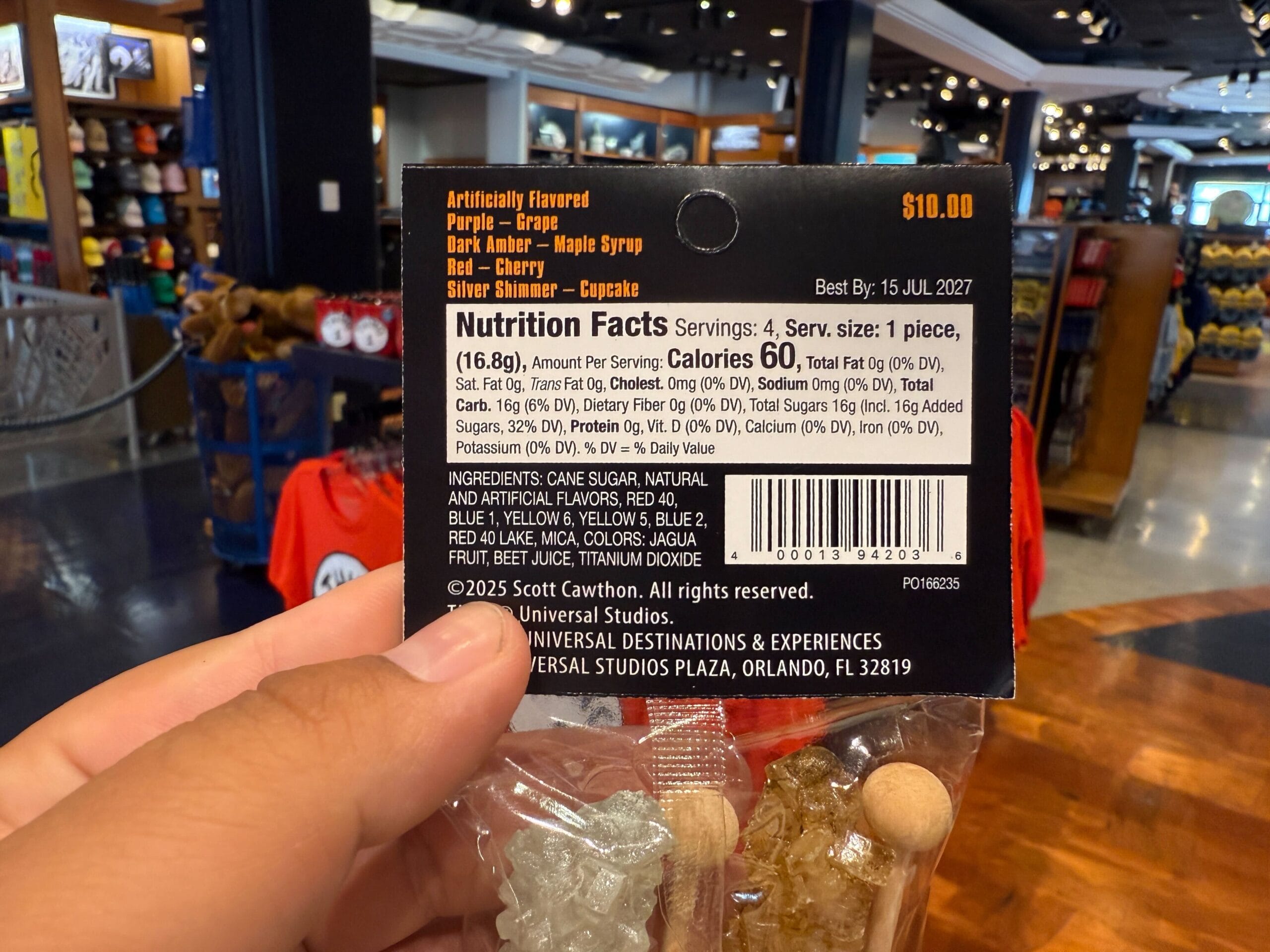 A hand holds a $10 candy pack with nutrition facts in a Universal Orlando Resort gift shop.
