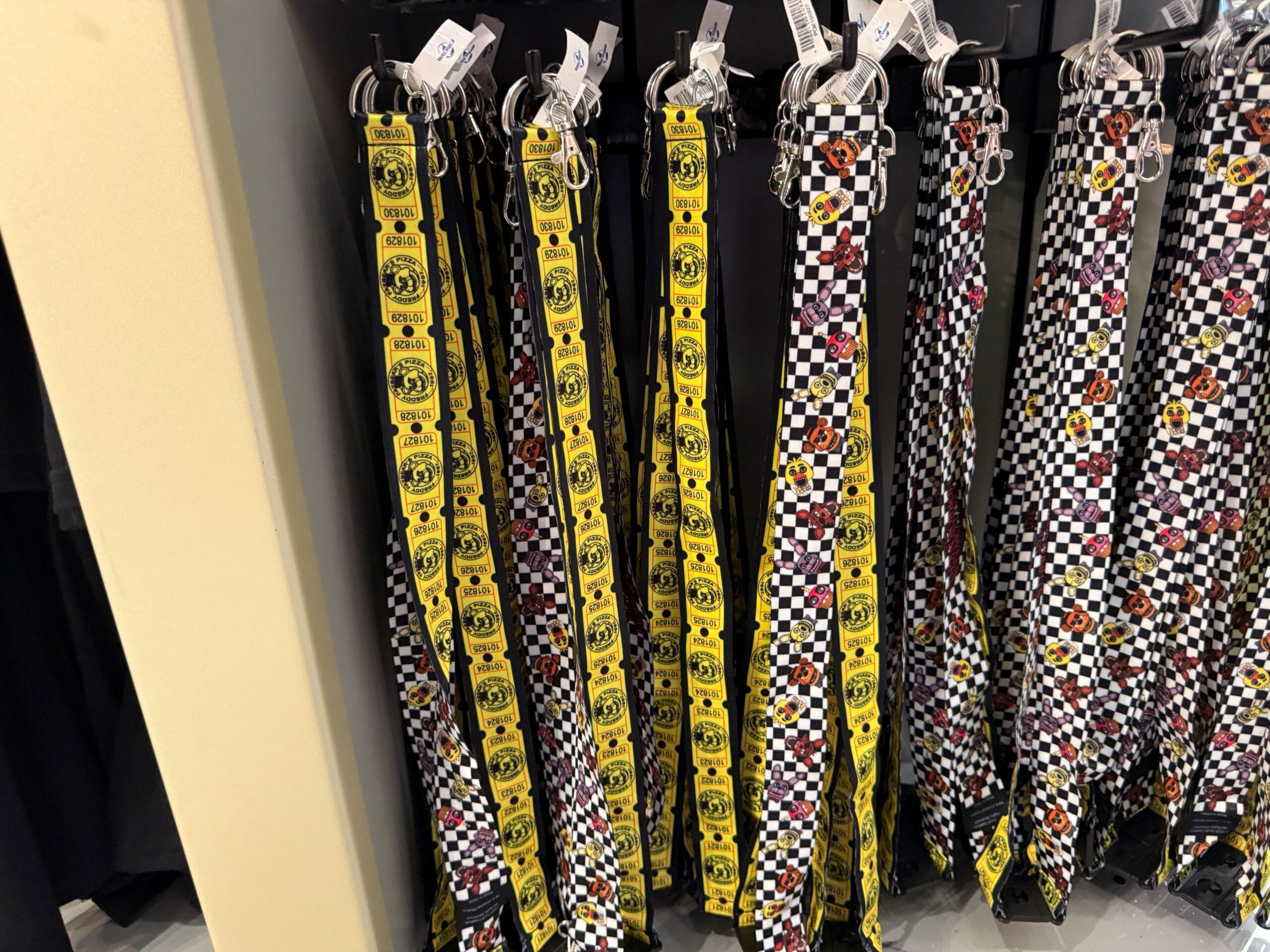 Belts with yellow smiley faces and checkerboard patterns hanging on display hooks at Universal Orlando Resort.