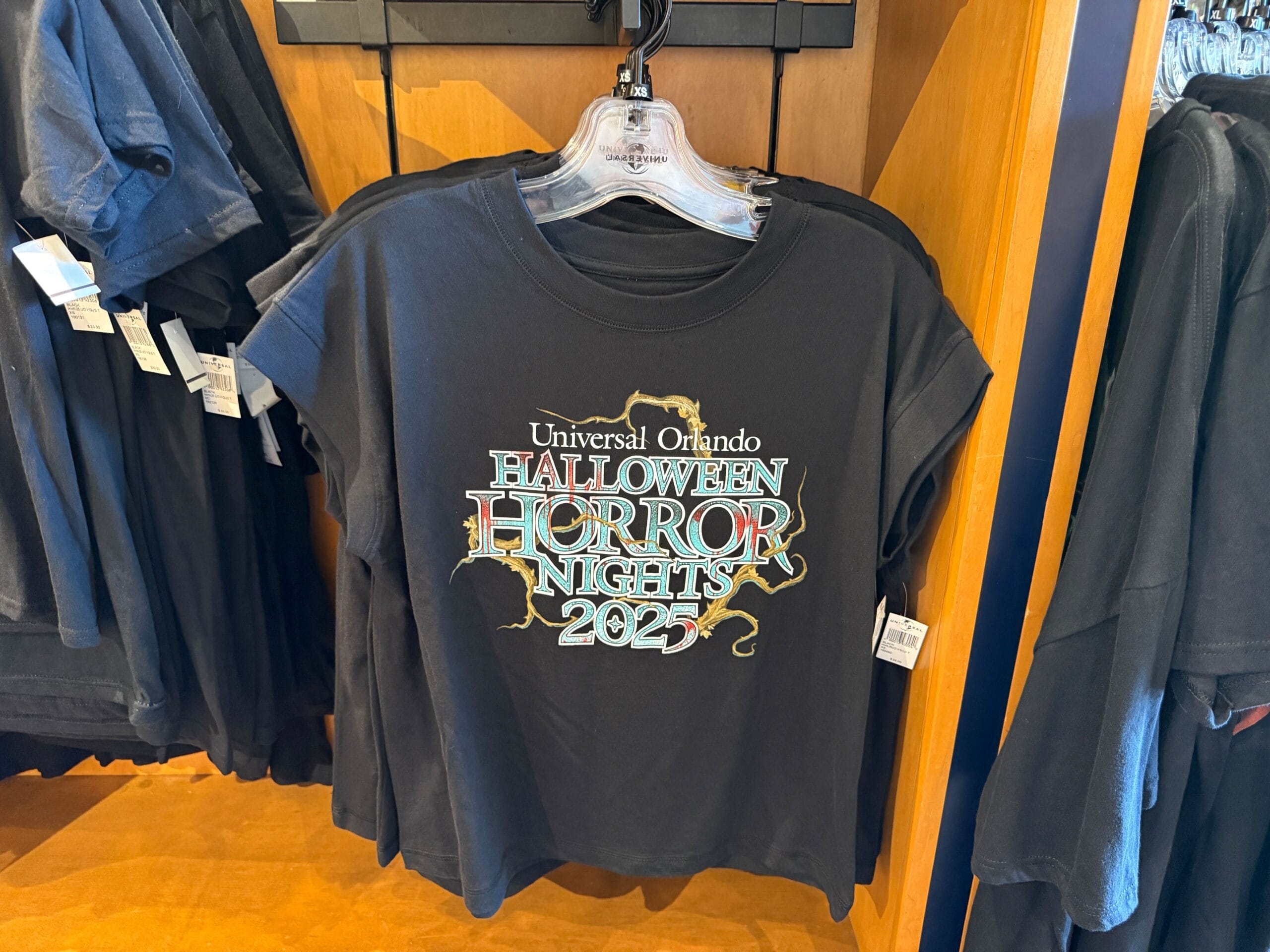 Black T-shirt on a rack features "Universal Orlando Halloween Horror Nights 2023"—a must-have Universal Orlando Resort HHN merch.