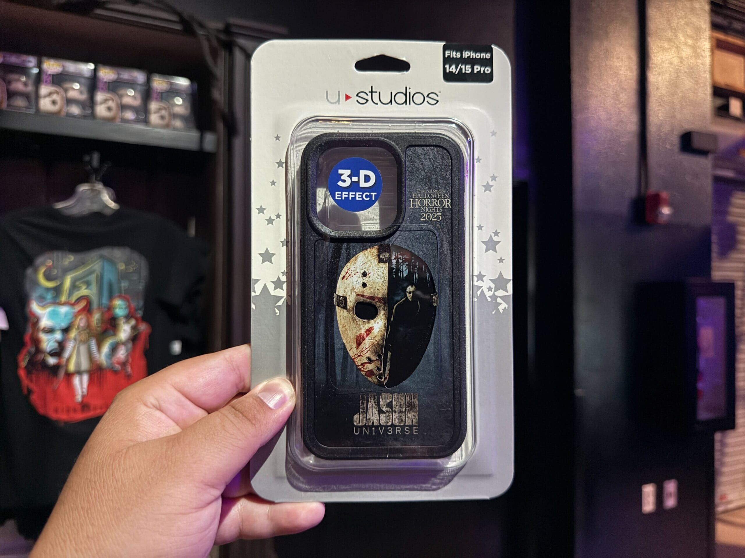Hand holding a Jason Voorhees 3D phone case—perfect HHN merch for iPhone 14/15 Pro, displayed in retail packaging.