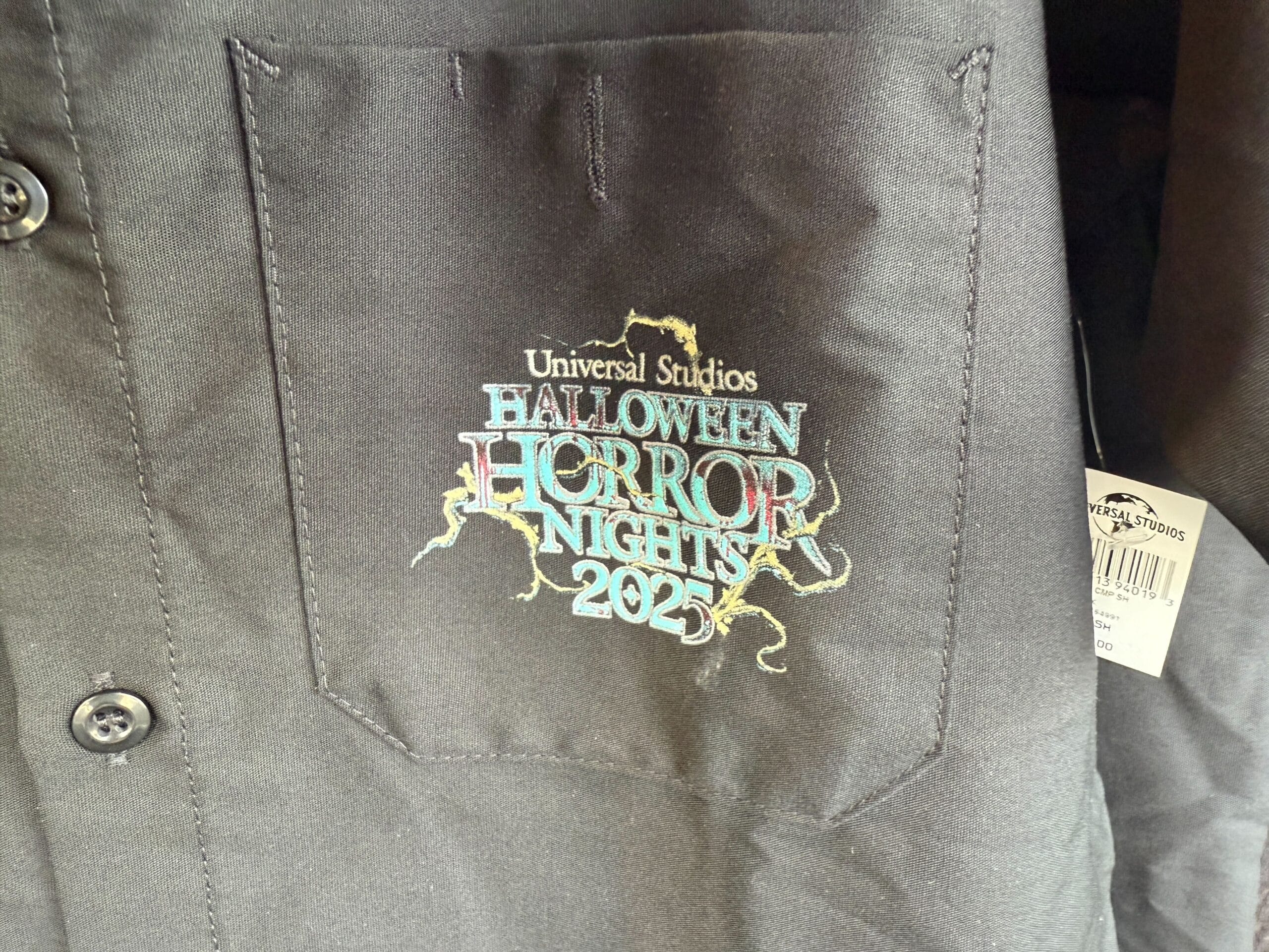 Black shirt pocket features colorful, cracked "Universal Studios Halloween Horror Nights 2024" logo—perfect HHN merch!