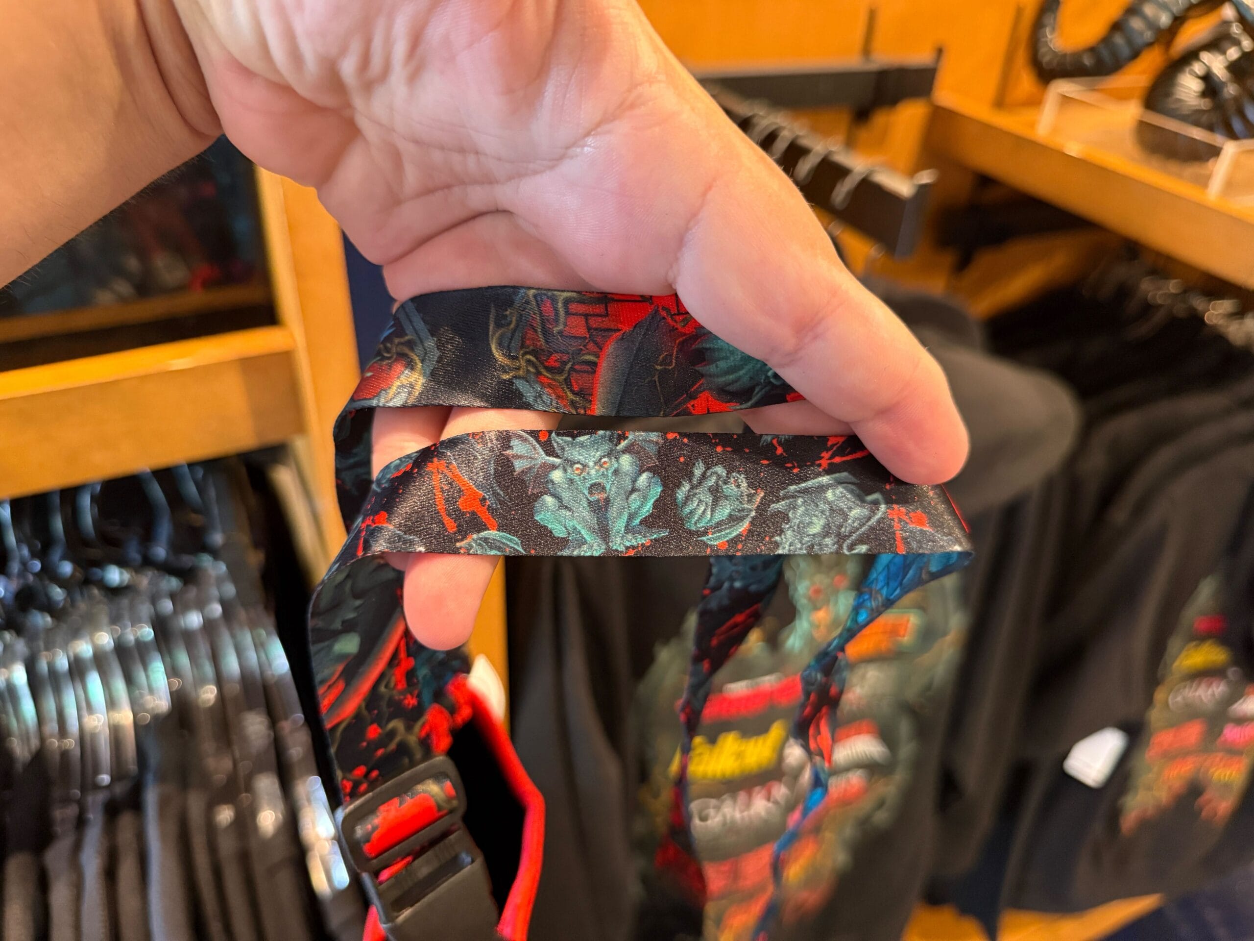 A hand holds a patterned lanyard with dark, colorful designs—perfect HHN Merch at Universal Orlando Resort.