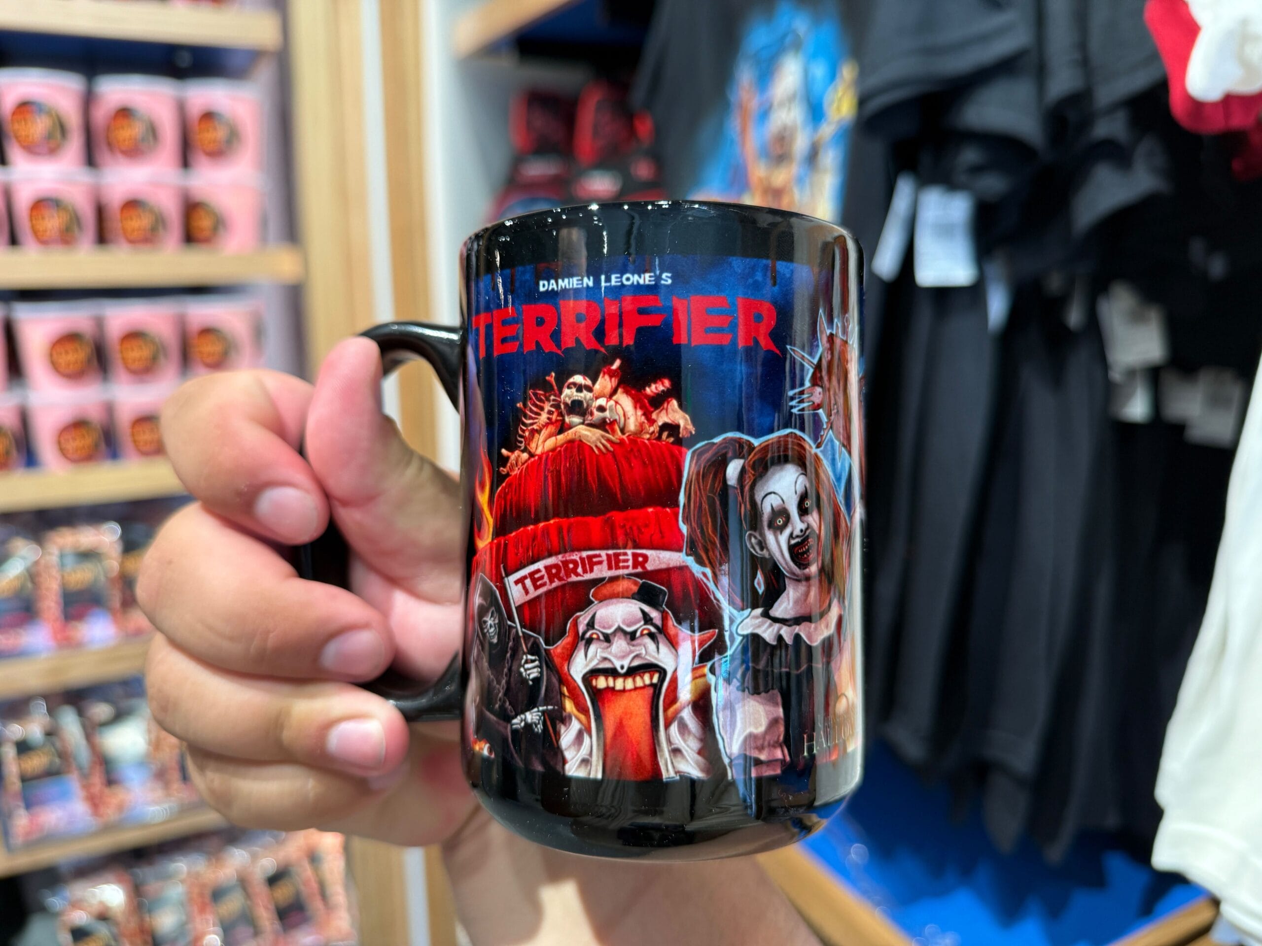 A hand holds a "Terrifier" mug, perfect HHN Merch for Halloween Horror Nights 2025 at Universal Orlando Resort.