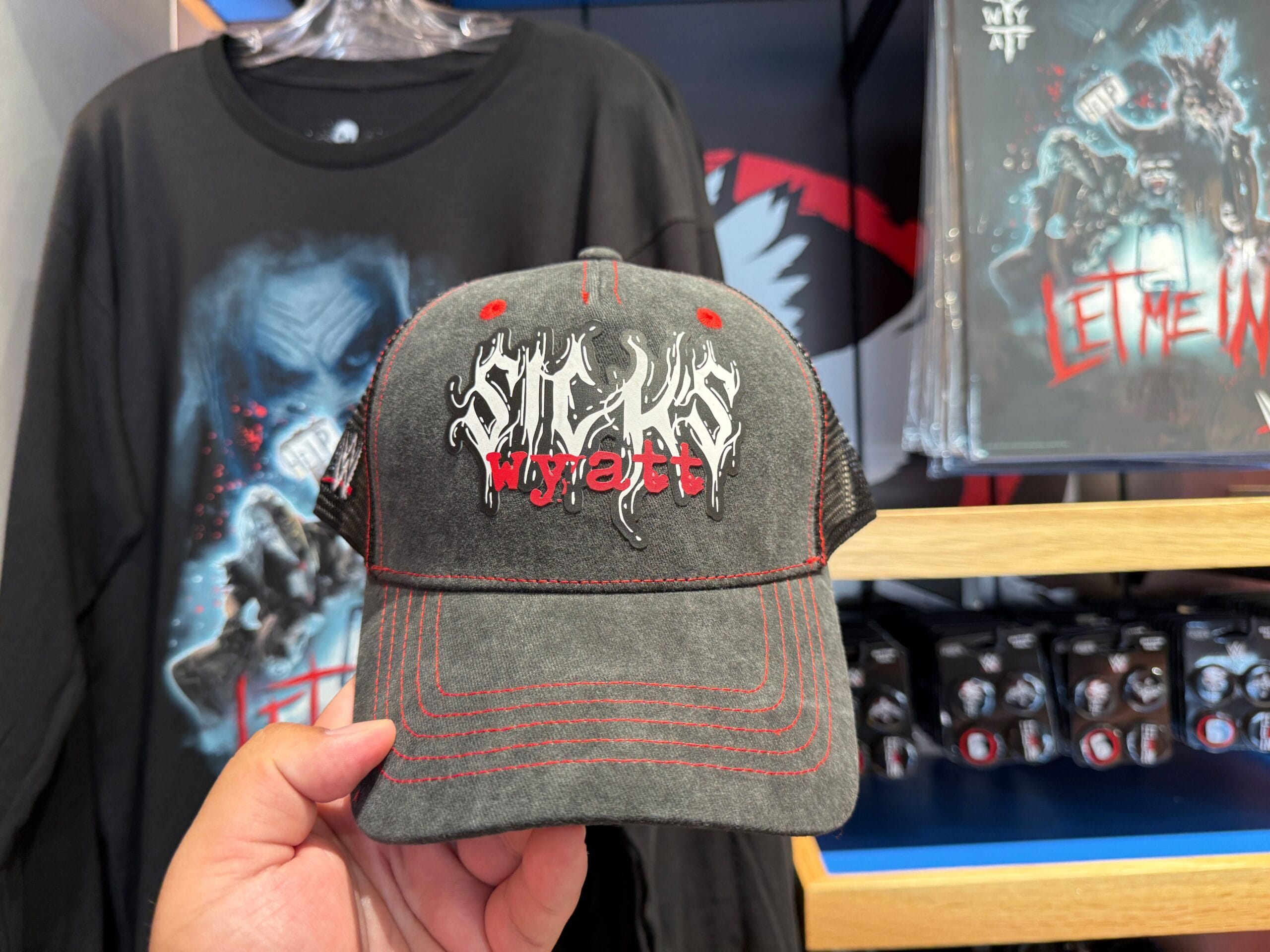 A hand holds a gray cap with "SIXTY WYATT" in bold text, shown among HHN merch at Universal Orlando Resort.